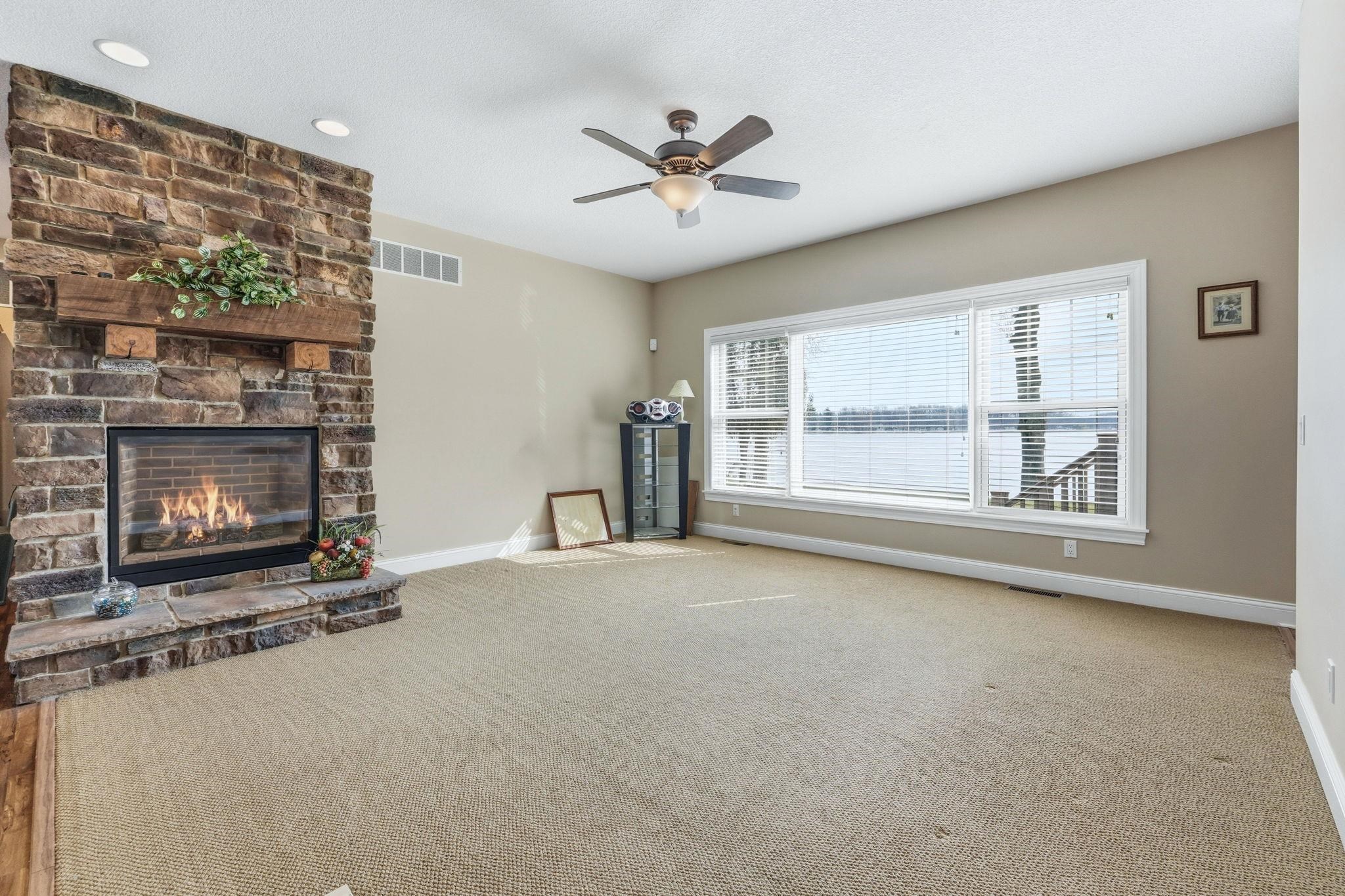 Unfurnished living room featuring a fireplace, ceiling fan, and carpet flooring