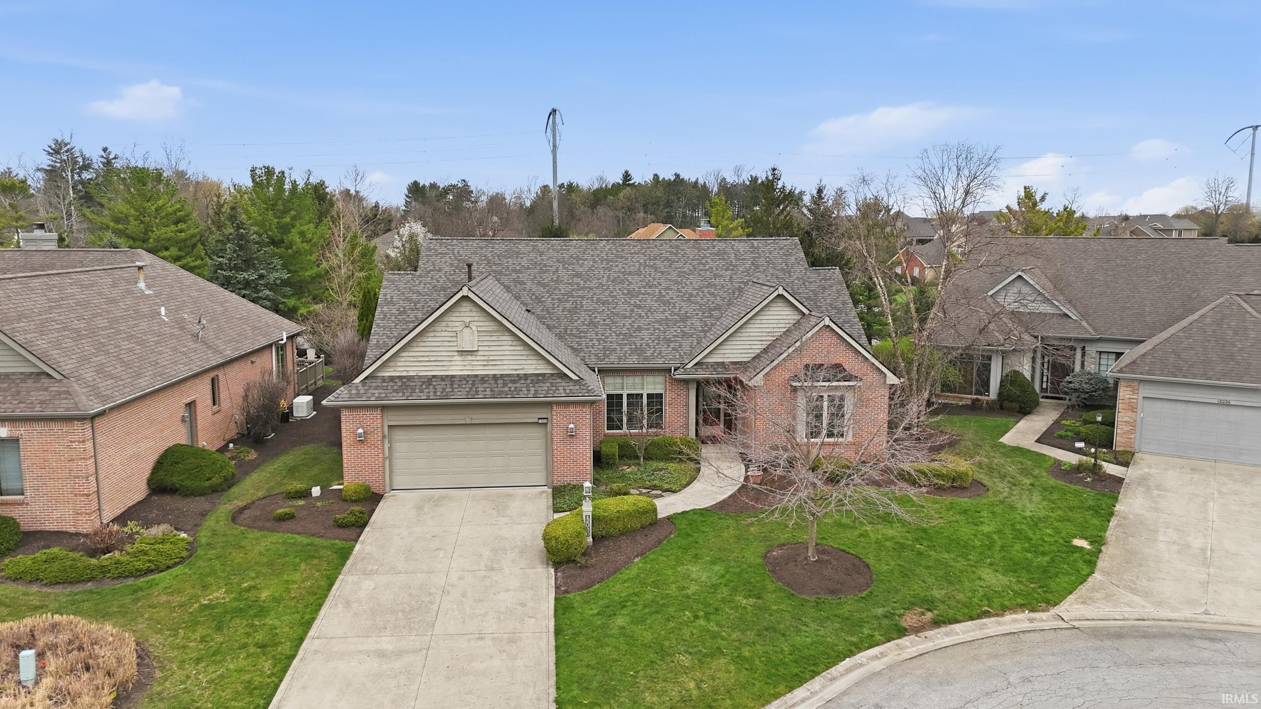 Traditional-style house featuring roof with shingles, a front lawn, brick siding, concrete driveway, and an attached garage