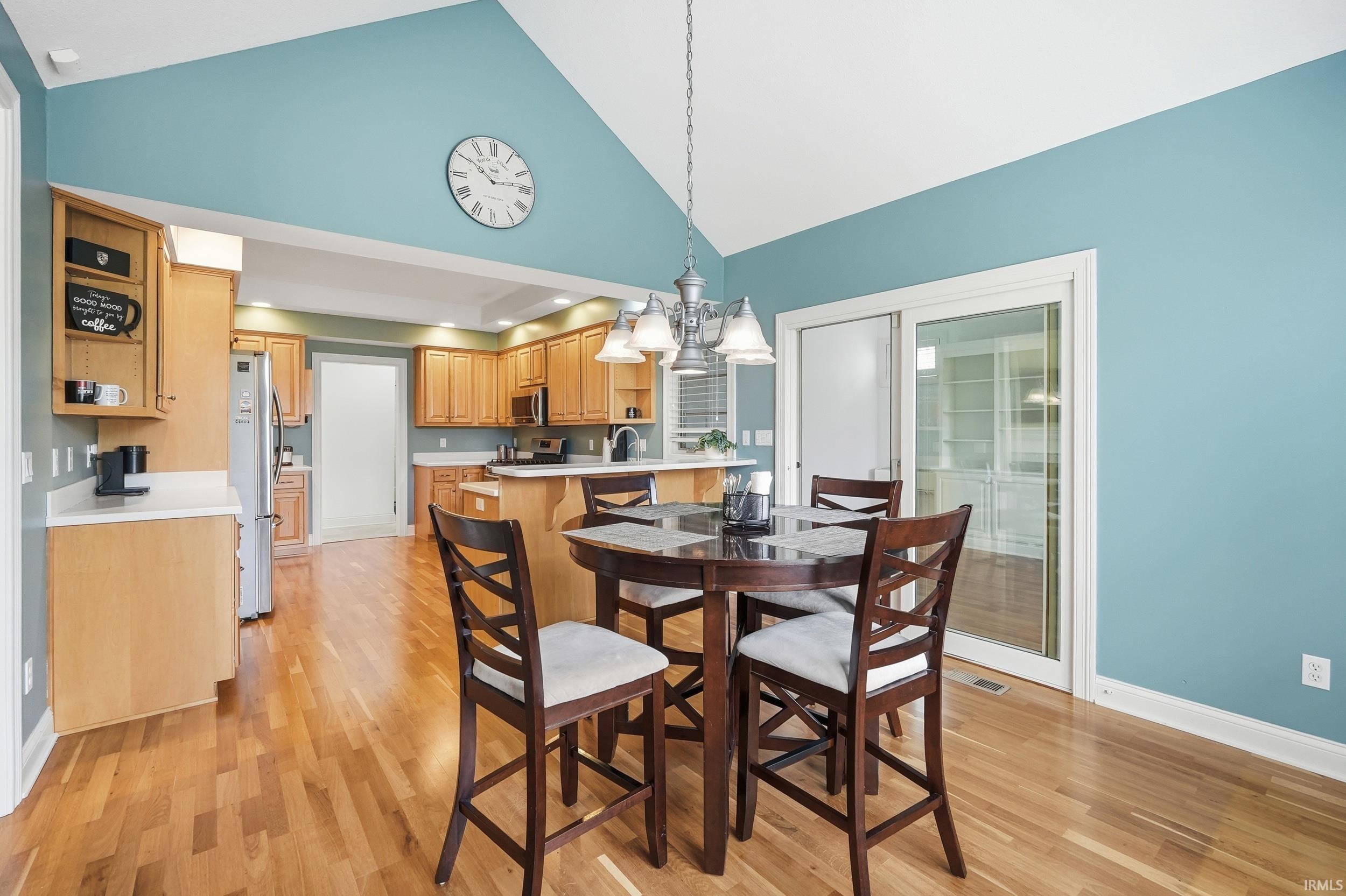 Dining space featuring hanging lights, light wood-type flooring, and lofted ceiling