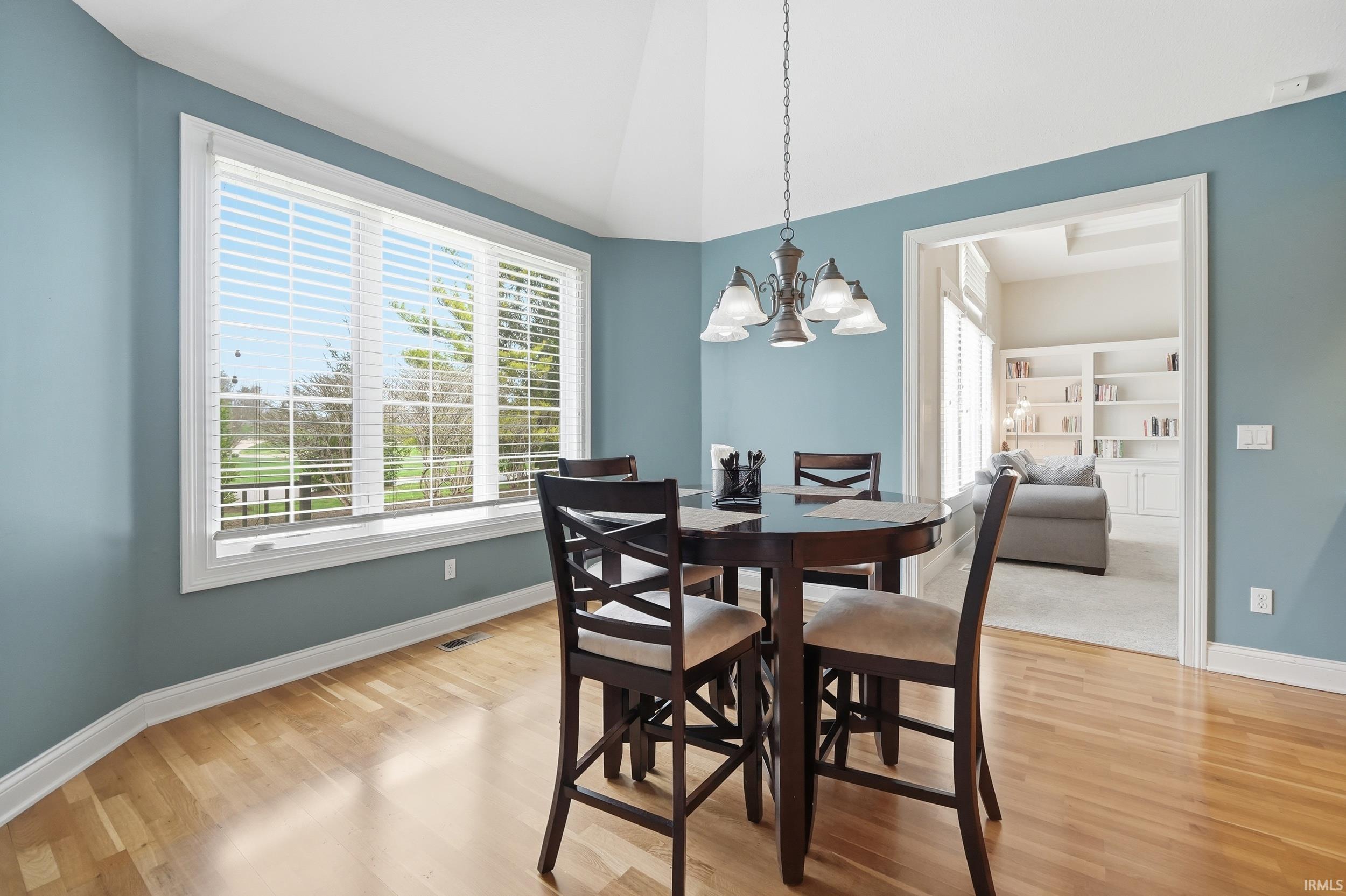 Dining area with hanging lights, light wood-type flooring, and vaulted ceiling