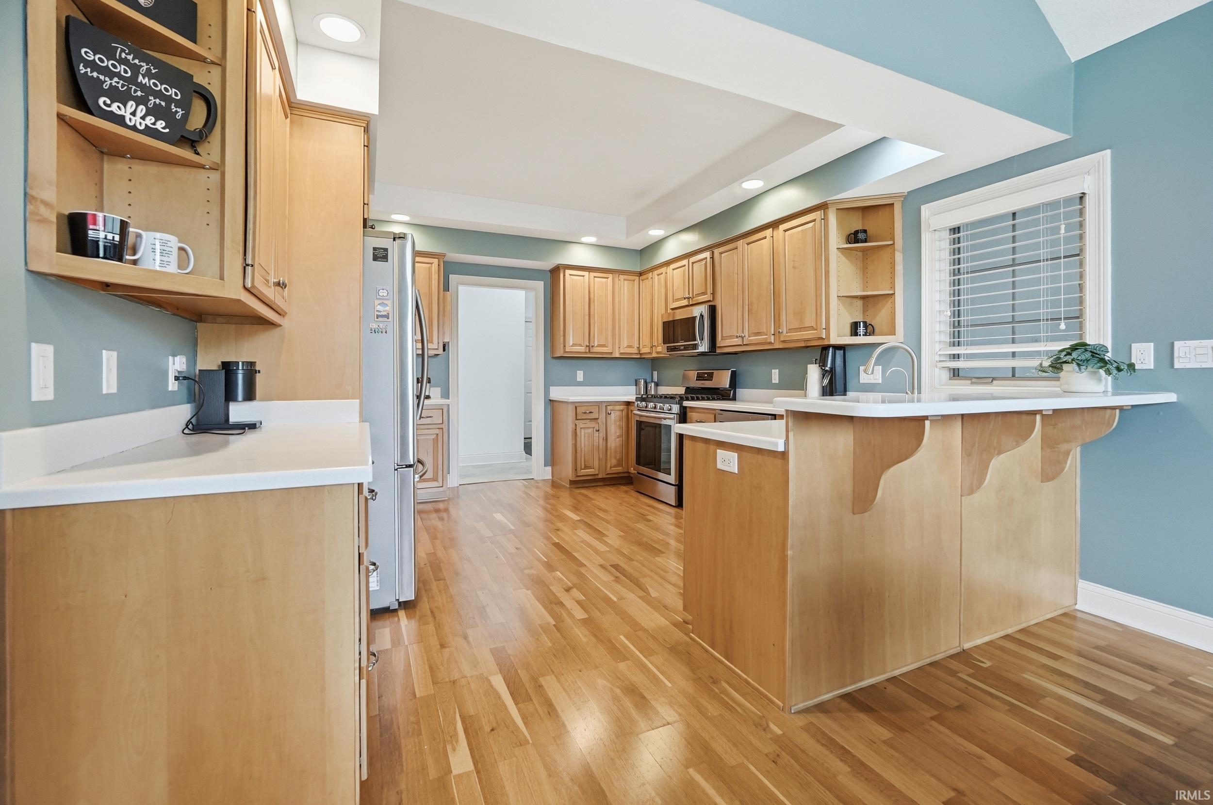 Kitchen with open shelves, a peninsula, stainless steel appliances, recessed lighting, and light countertops