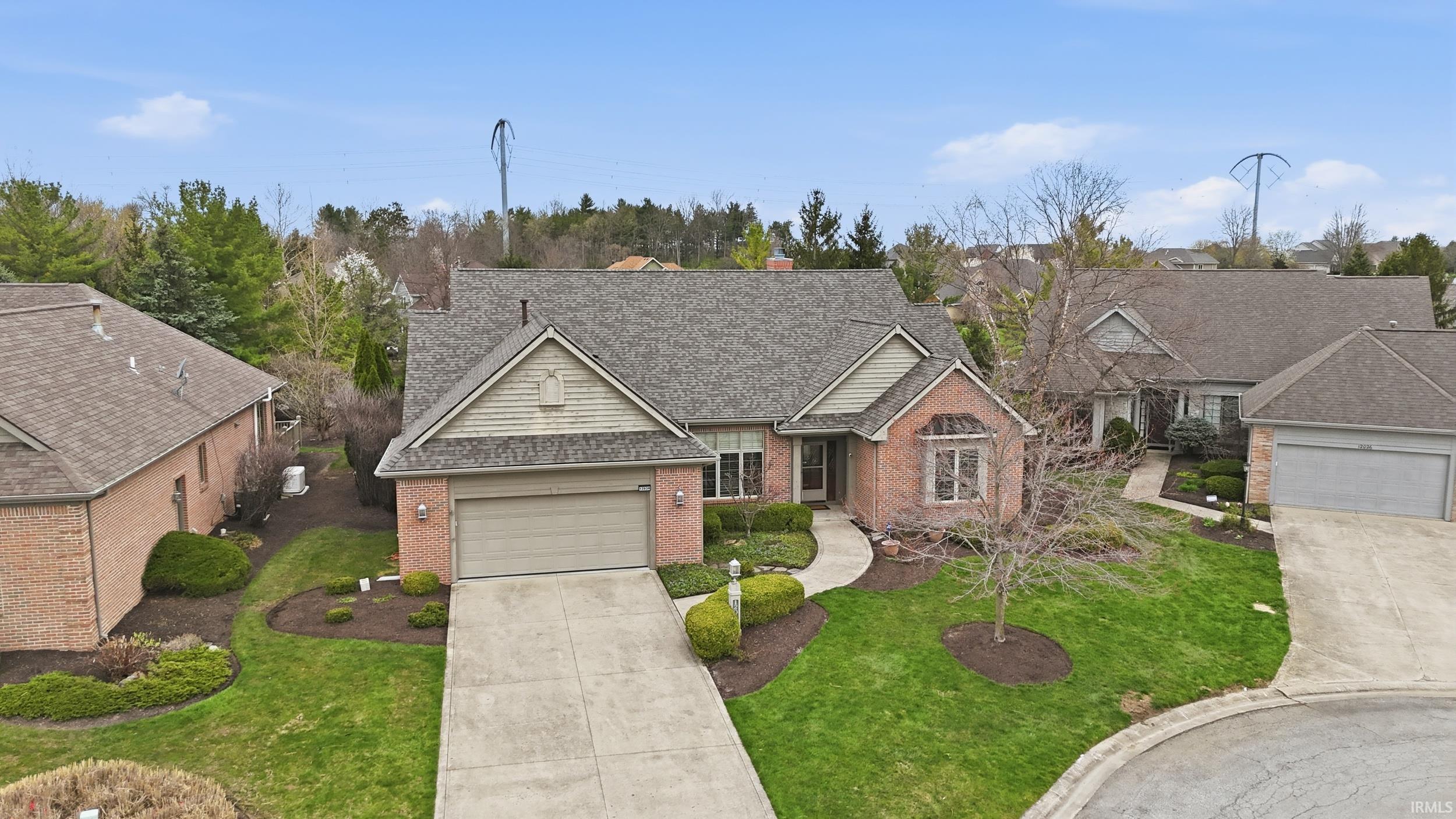 Traditional home featuring roof with shingles, a front yard, brick siding, and driveway