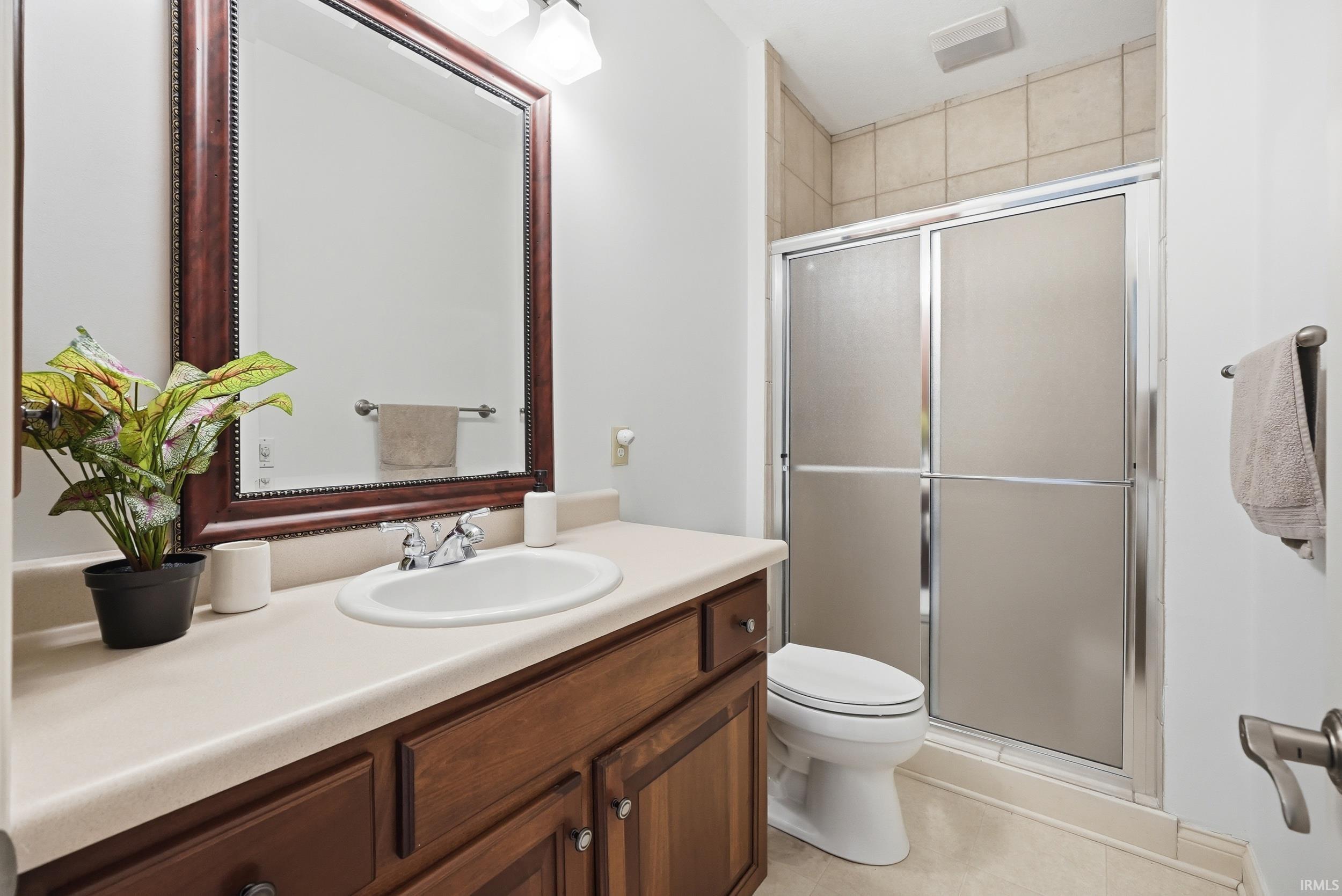 Full bathroom featuring vanity, a shower stall, and light tile patterned floors