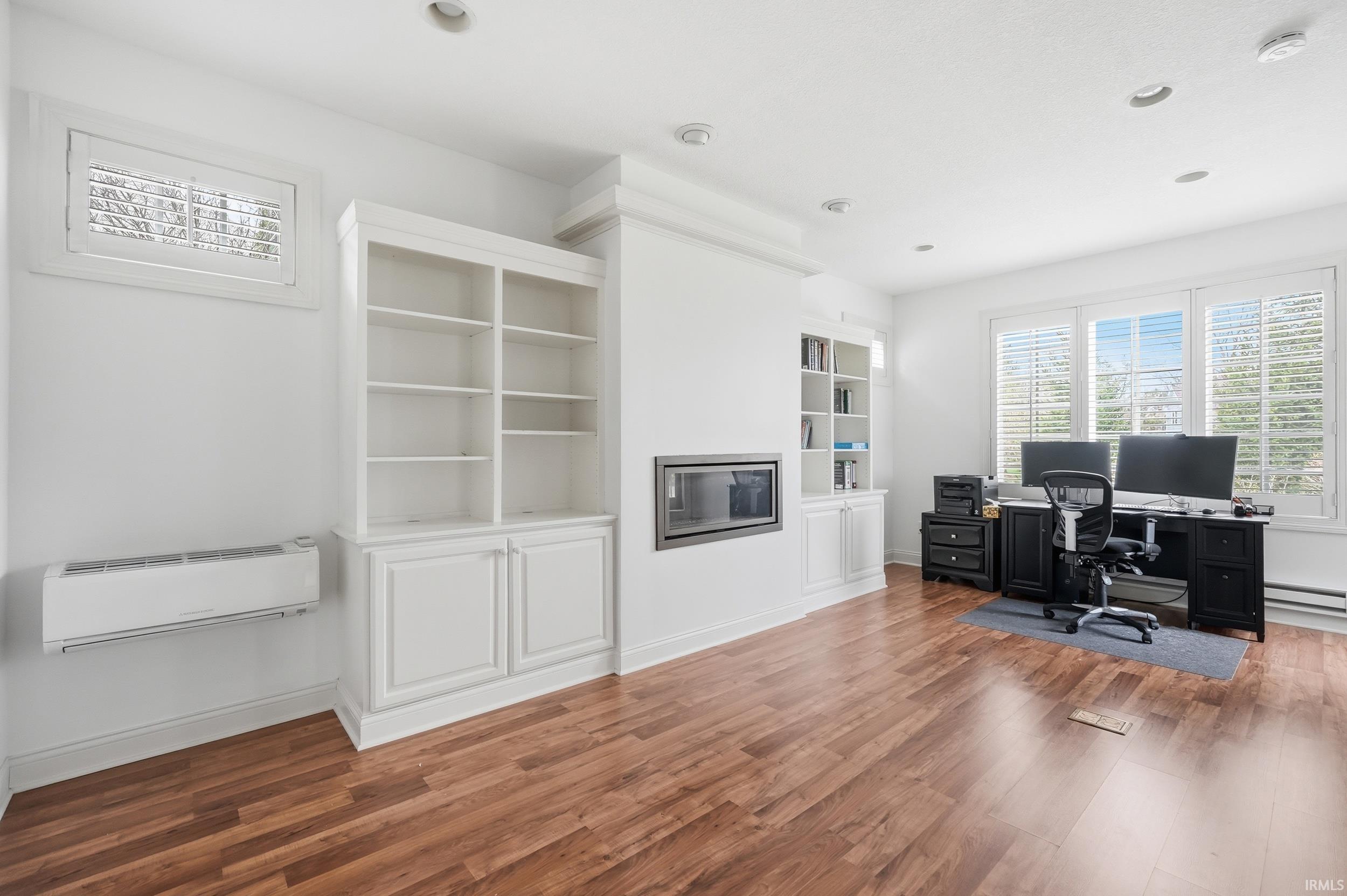 Office area with light wood-style flooring, a glass covered fireplace, recessed lighting, and a baseboard radiator