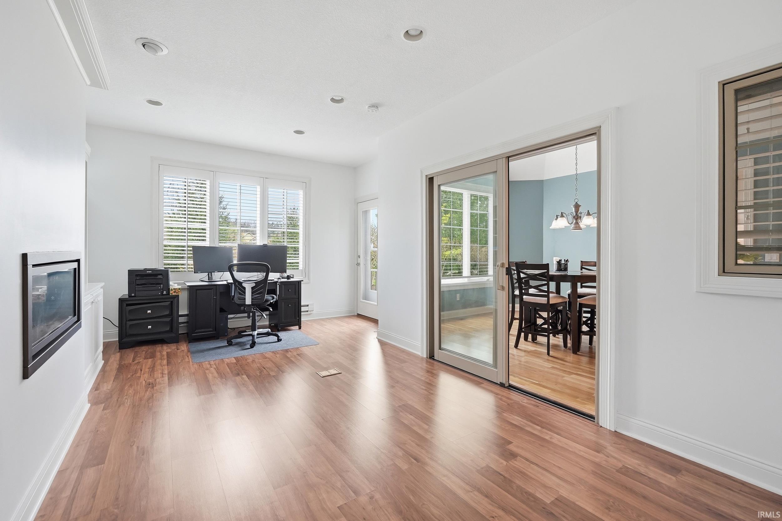 Office space with light wood finished floors, hanging lights, and a glass covered fireplace
