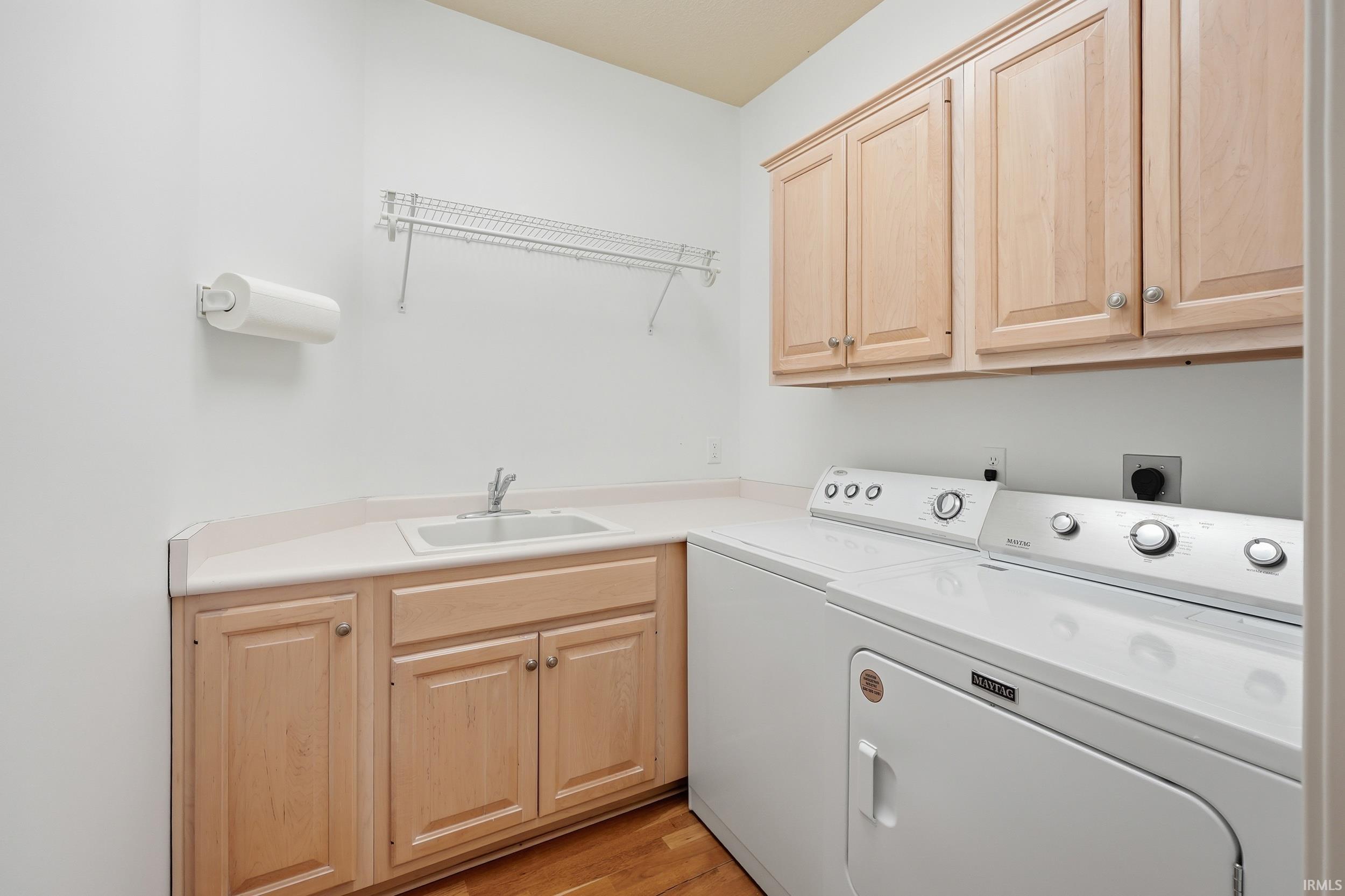 Laundry room featuring light wood-type flooring, cabinet space, and washing machine and clothes dryer