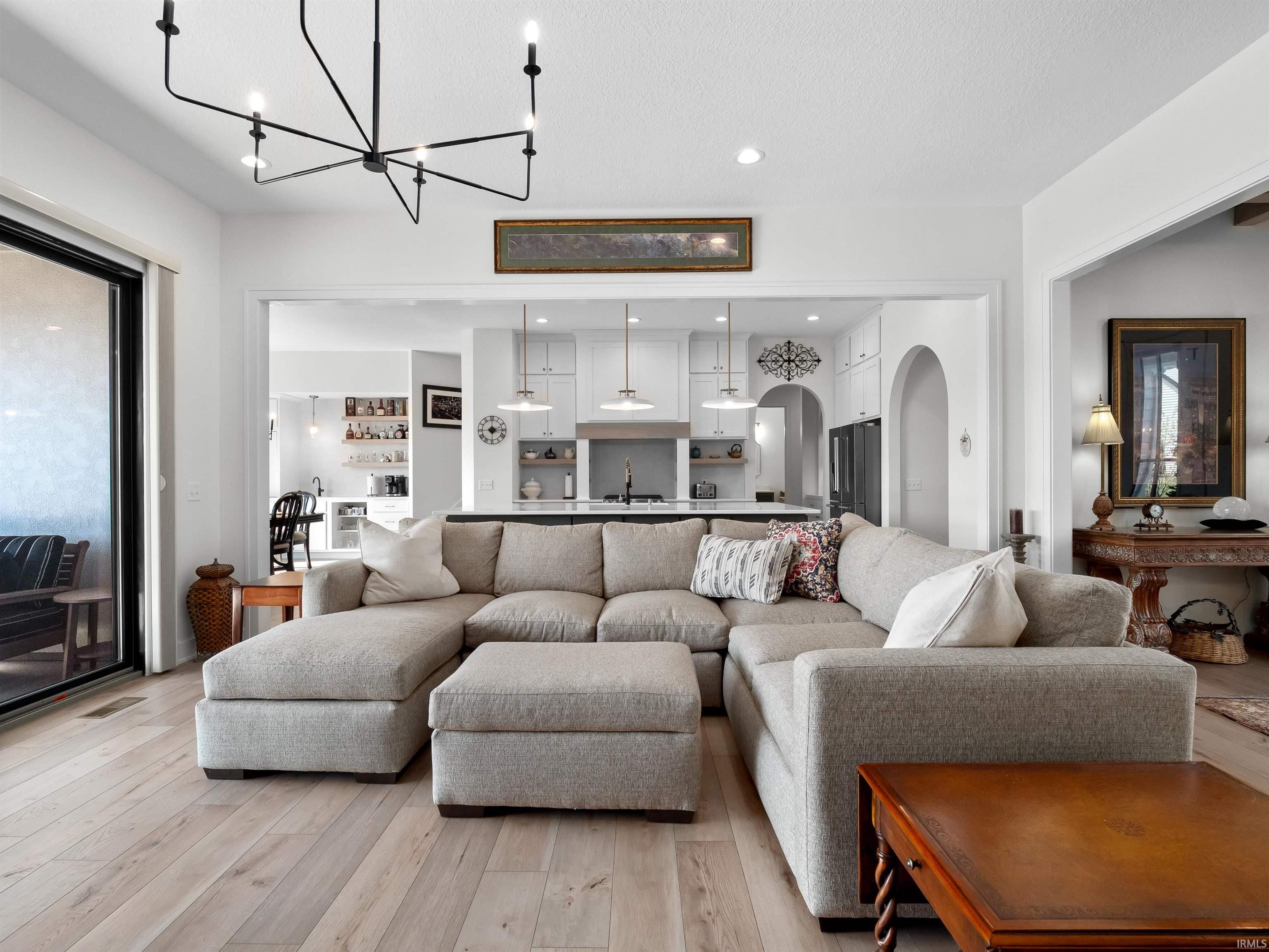 Living room with light wood-style floors, arched walkways, recessed lighting, and a chandelier
