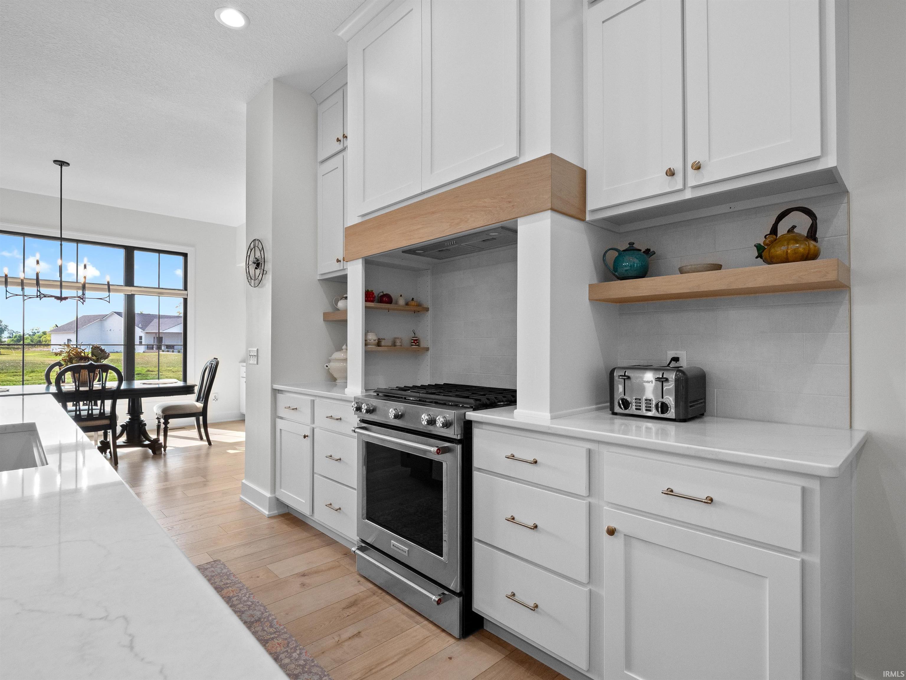 Kitchen featuring open shelves, white cabinetry, stainless steel gas stove, and recessed lighting