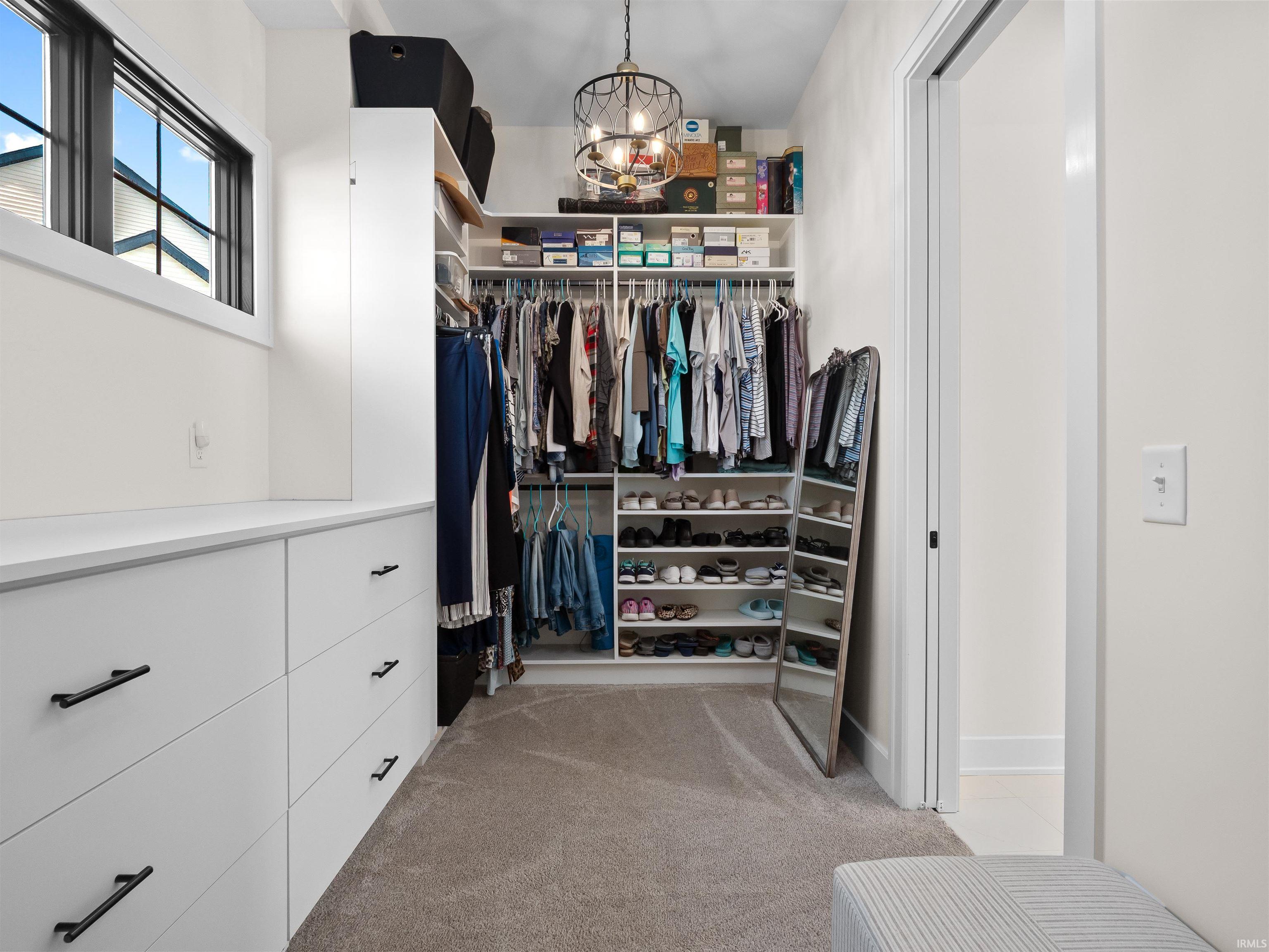 Spacious closet with a chandelier and light carpet