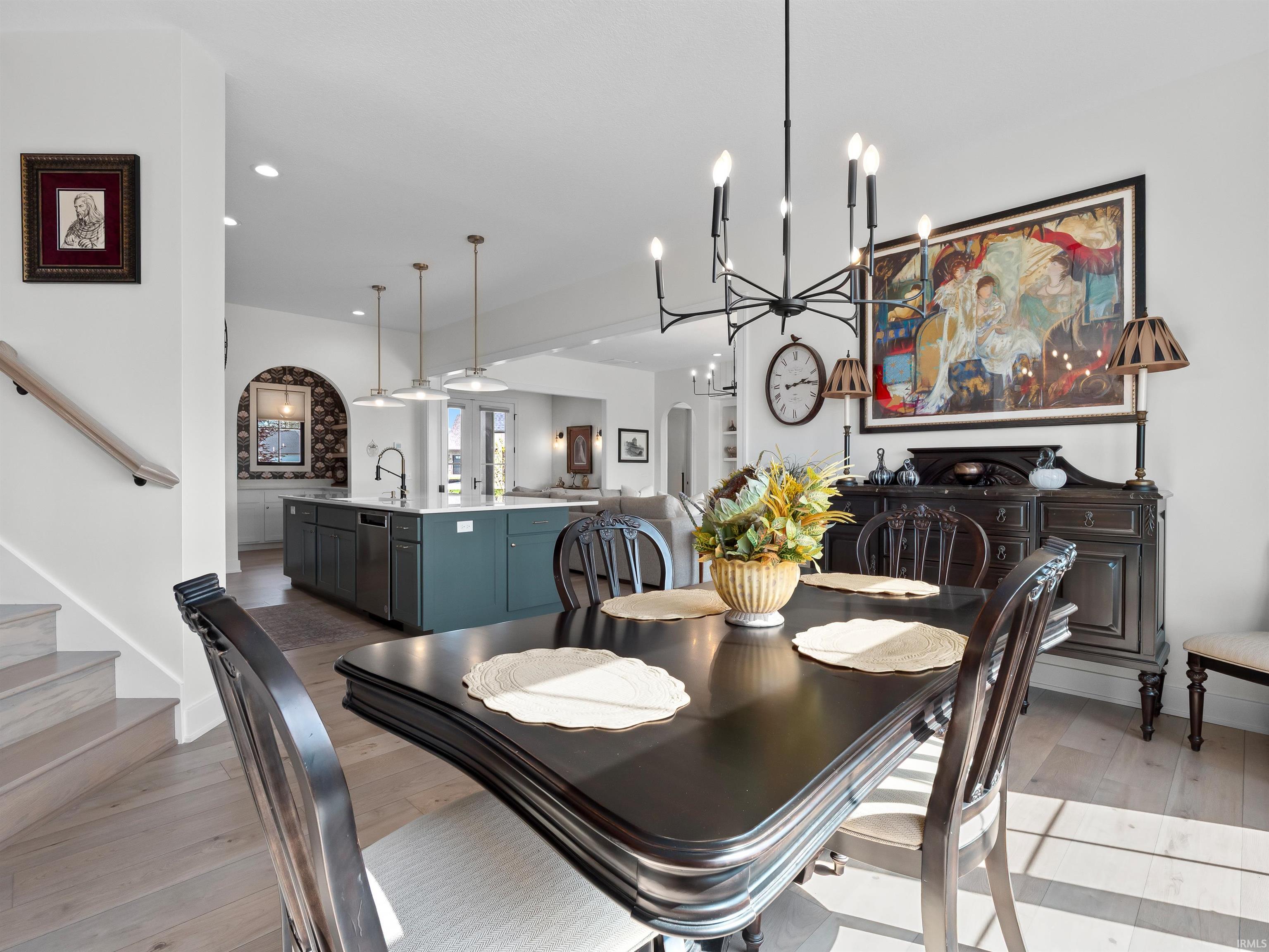 Dining area featuring light wood-type flooring, arched walkways, stairway, a chandelier, and recessed lighting