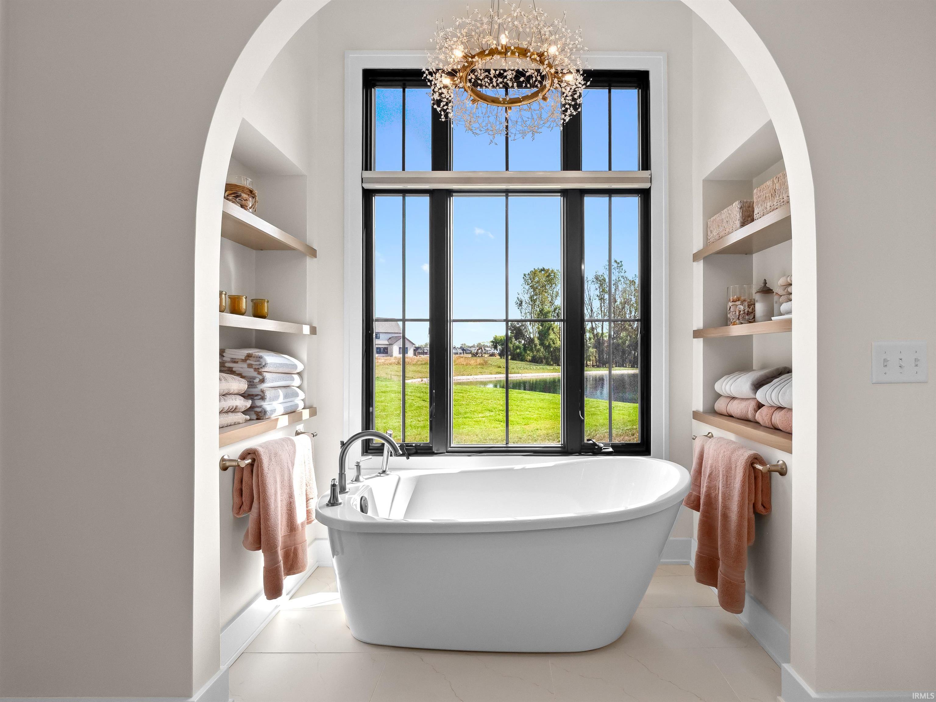 Bathroom with built in shelves, a soaking tub, a water view, and a chandelier