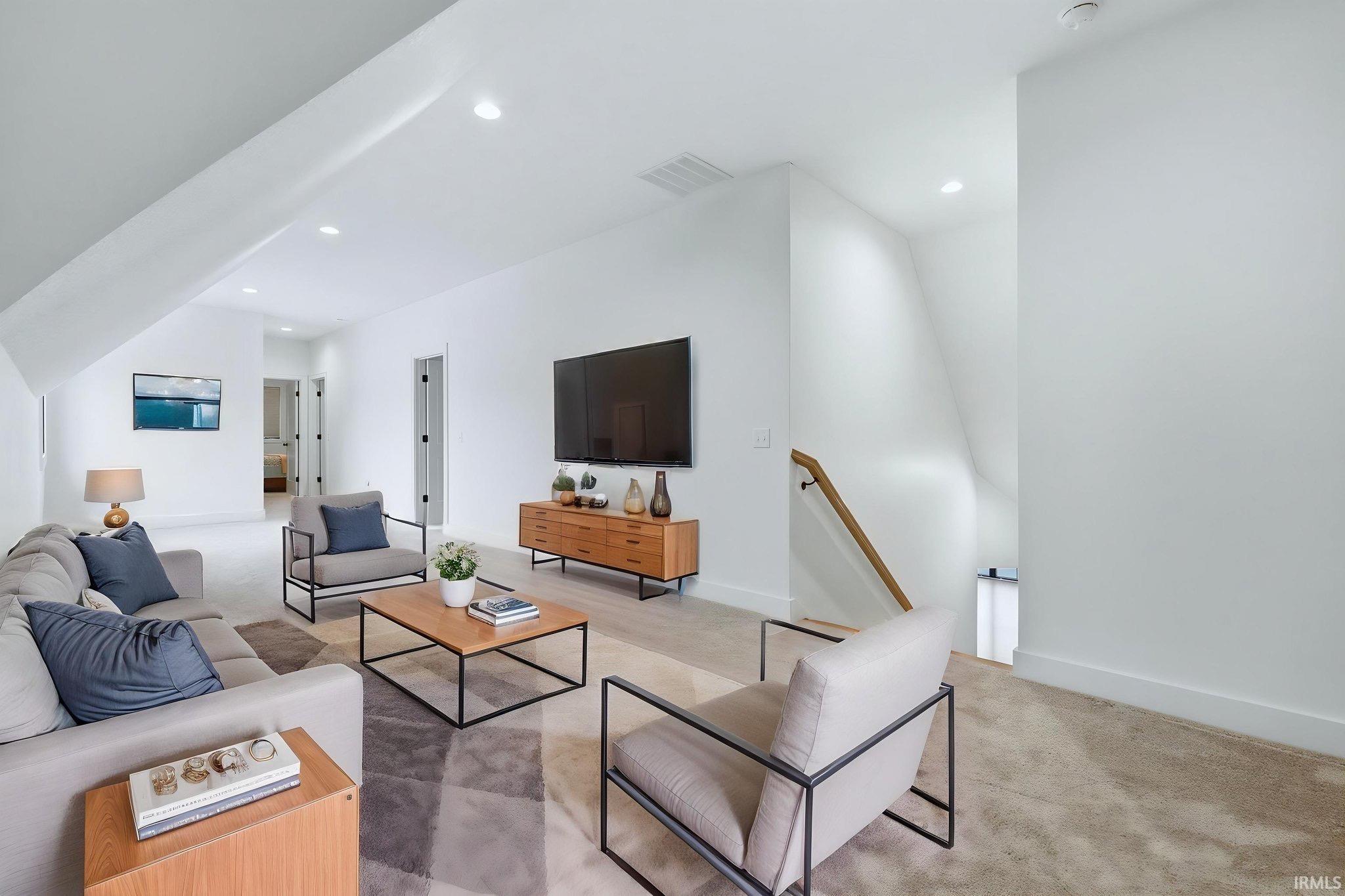 Living area featuring light colored carpet and recessed lighting
