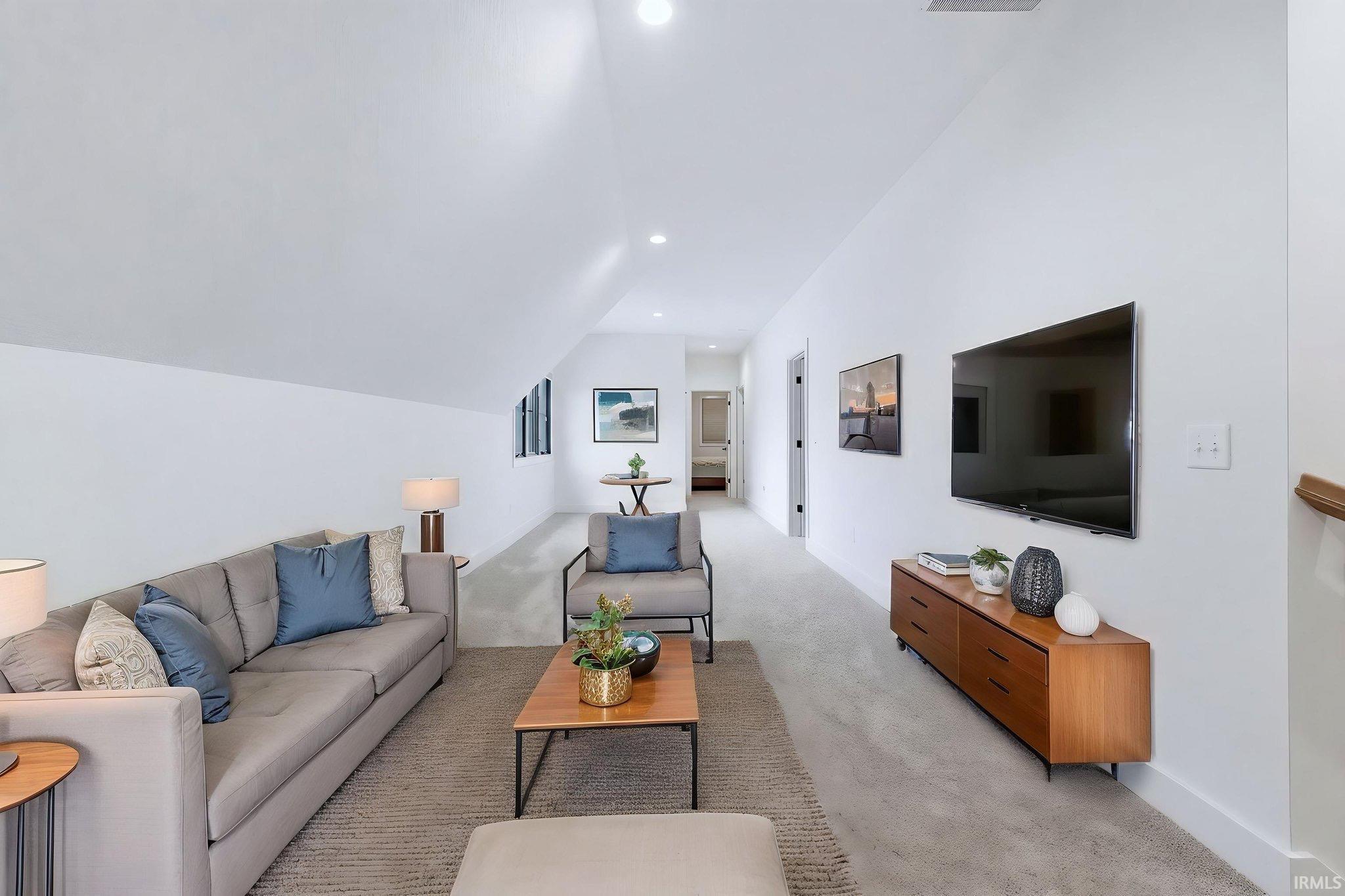 Living area featuring light carpet, vaulted ceiling, and recessed lighting
