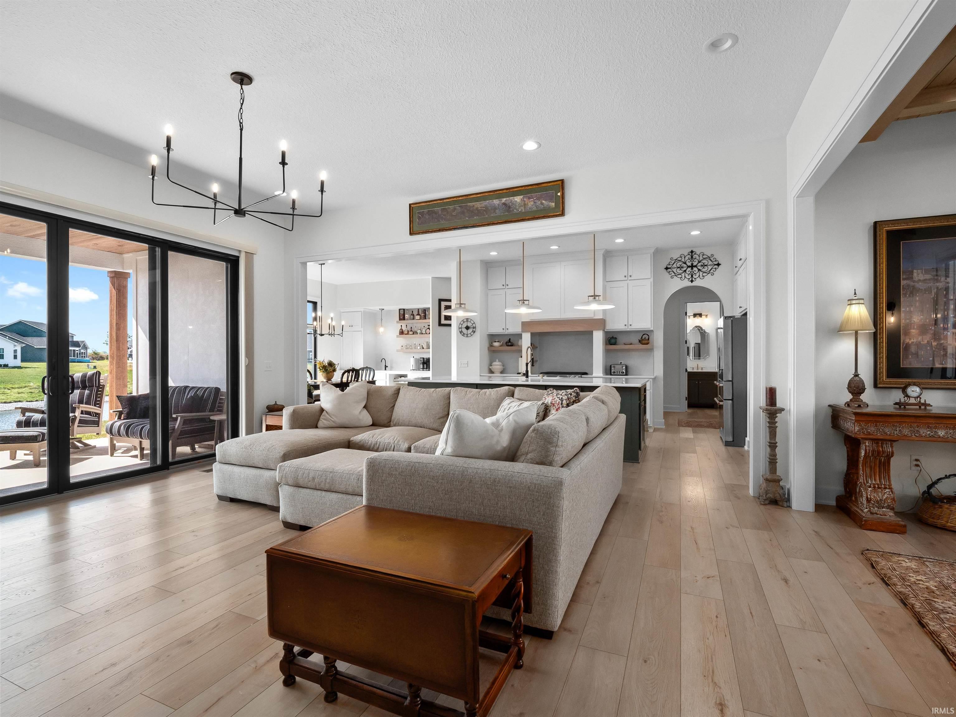 Living area with light wood-type flooring, arched walkways, a chandelier, and recessed lighting