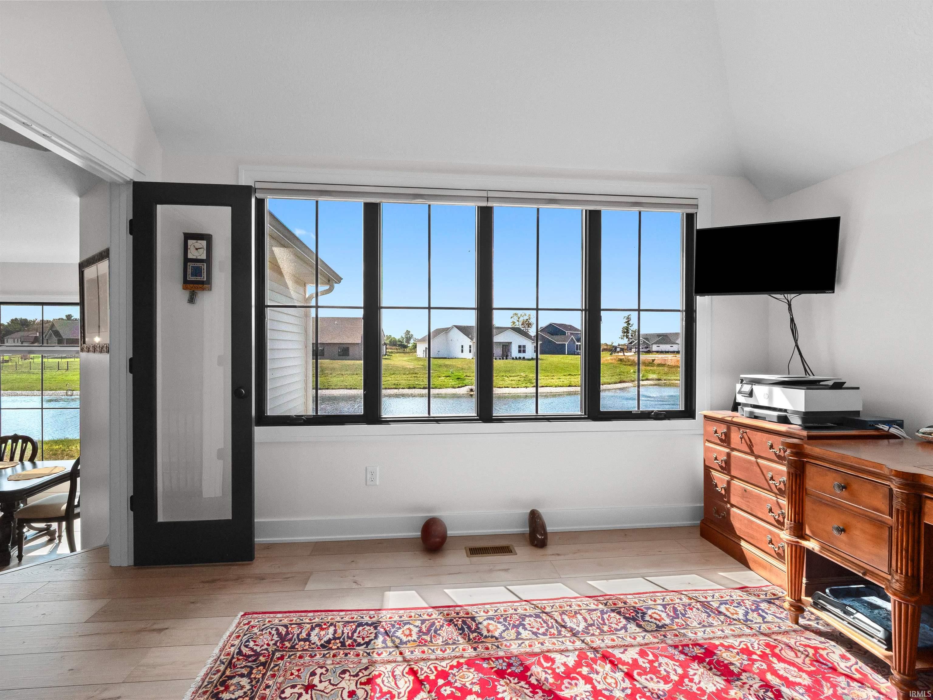 Office space with light wood-type flooring, plenty of natural light, lofted ceiling, and a residential view