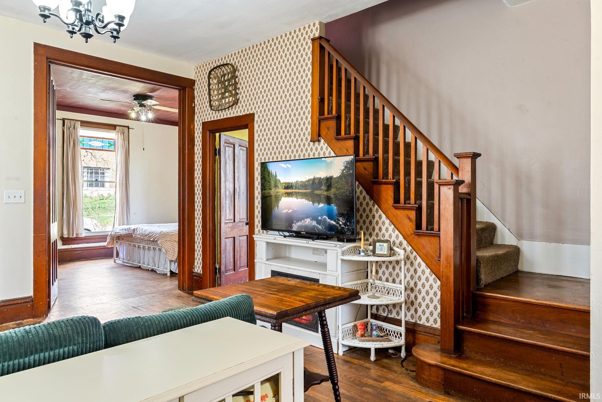 Staircase featuring wallpapered walls, wood finished floors, and a chandelier