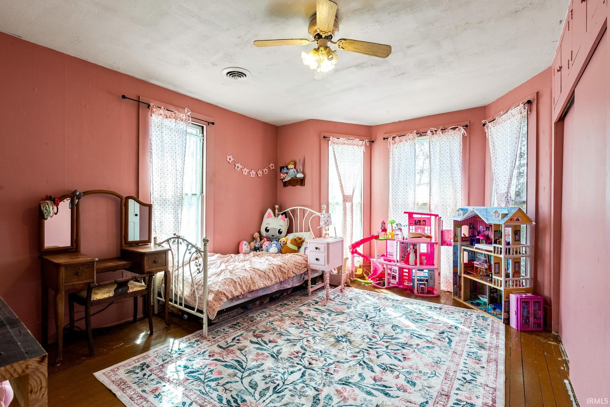 Bedroom featuring dark wood-style floors, multiple windows, and a ceiling fan