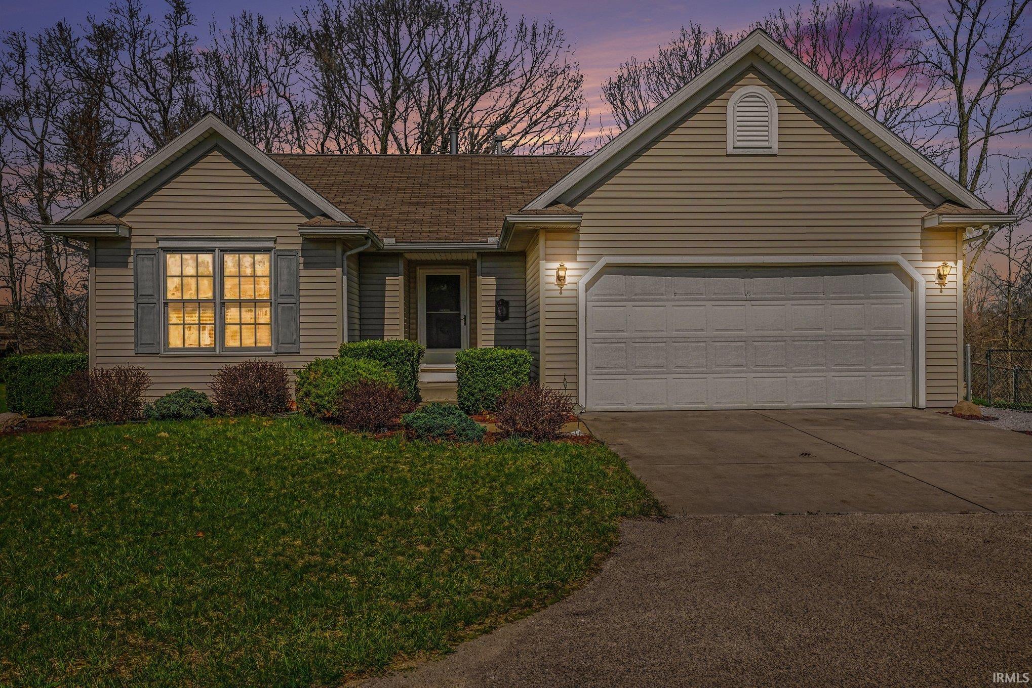 View of front of house featuring concrete driveway, an attached garage, and a yard