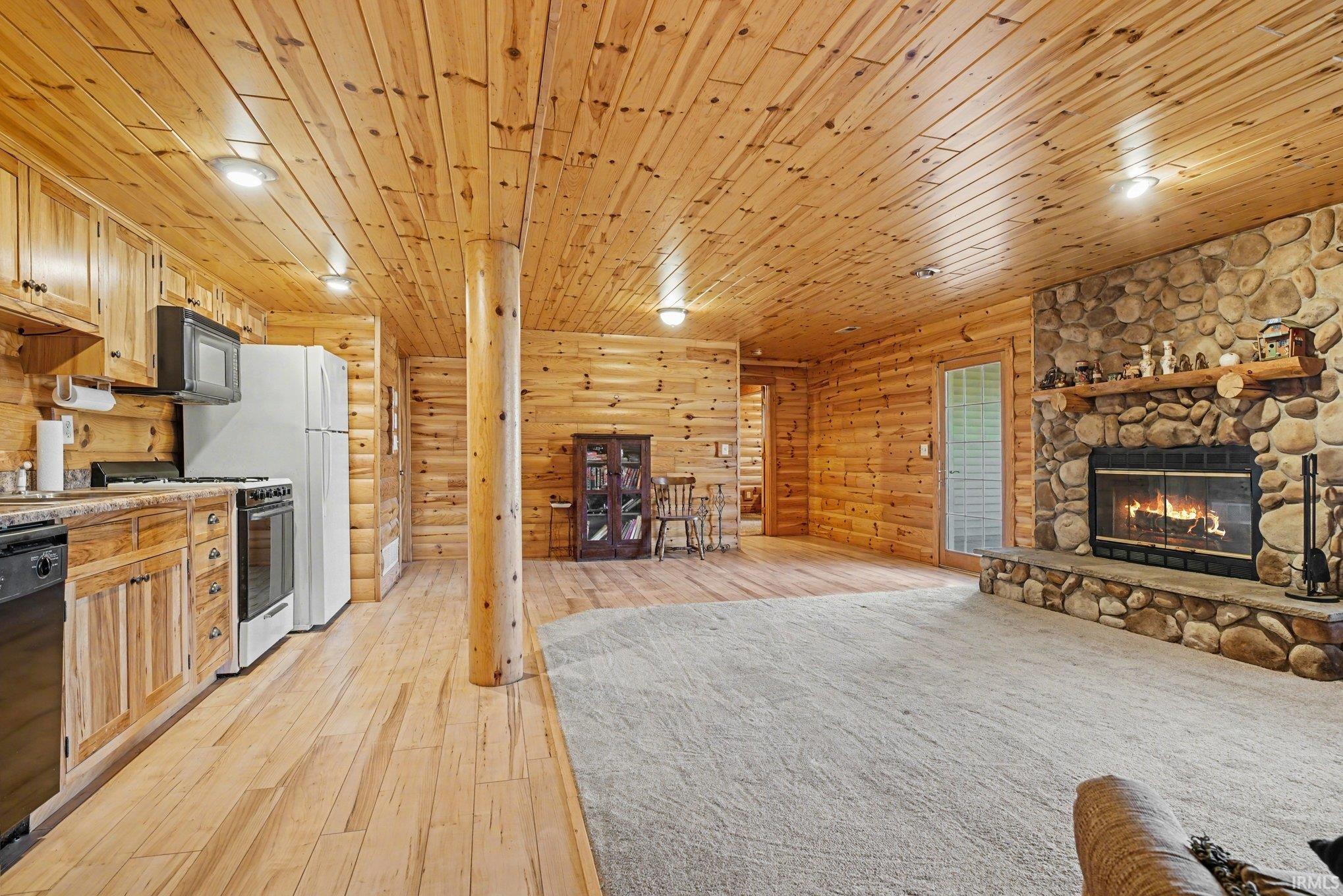 Kitchen with black appliances, wooden ceiling, open floor plan, light wood-style flooring, and light countertops