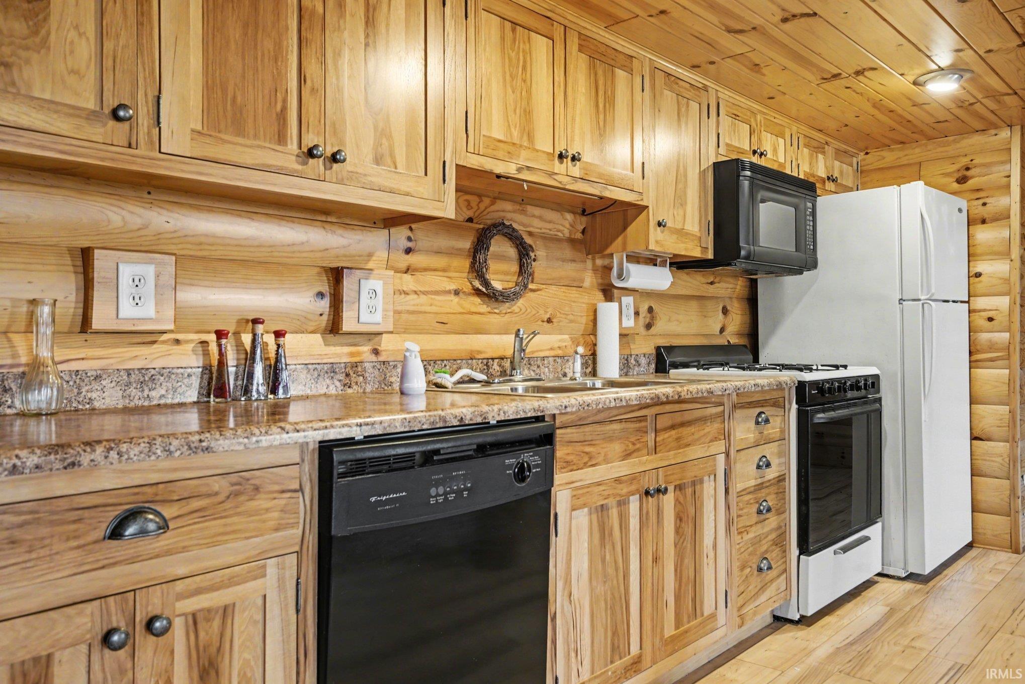 Kitchen with log walls, black appliances, wood ceiling, and light wood finished floors