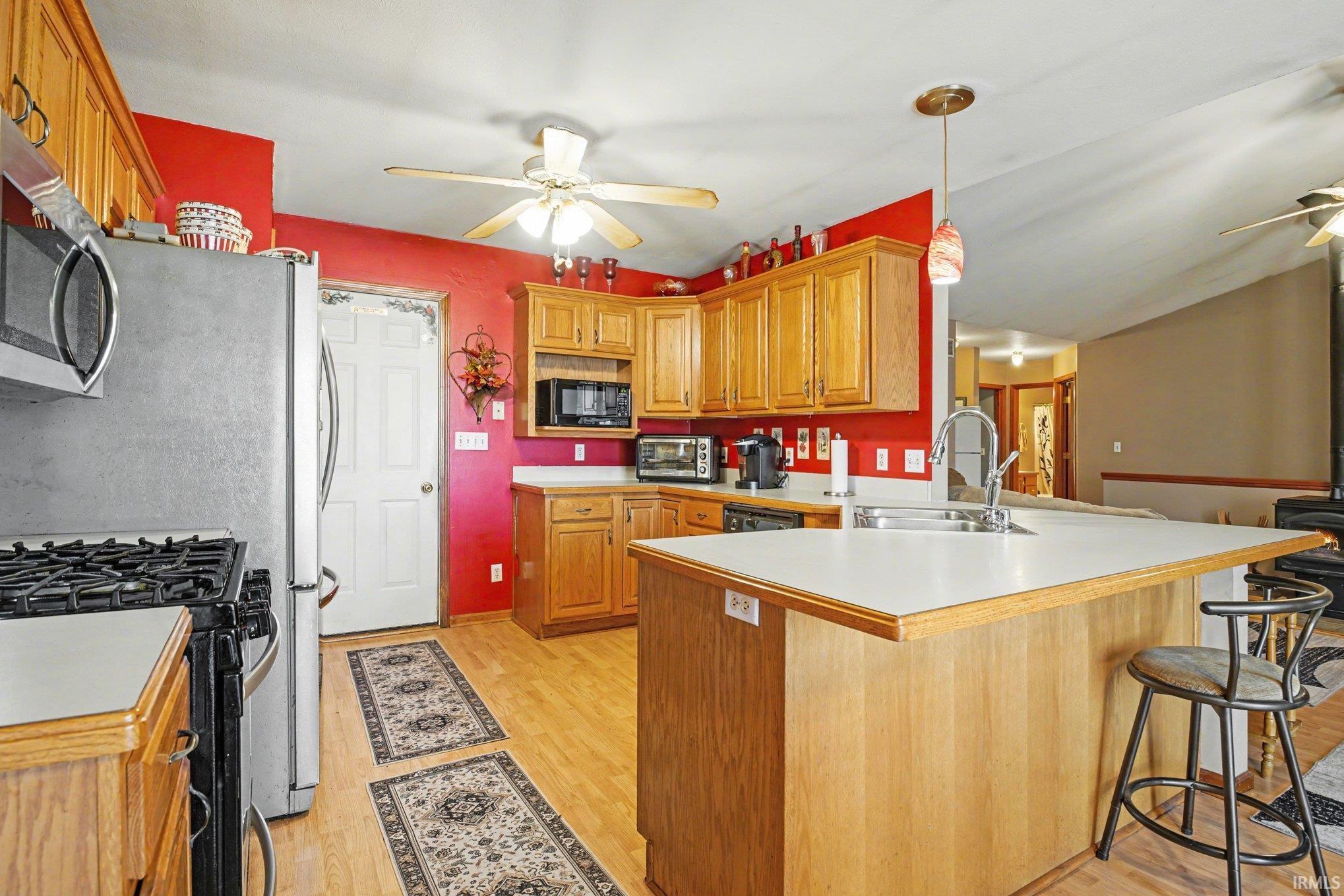 Kitchen with a ceiling fan, a kitchen bar, a peninsula, pendant lighting, and light countertops