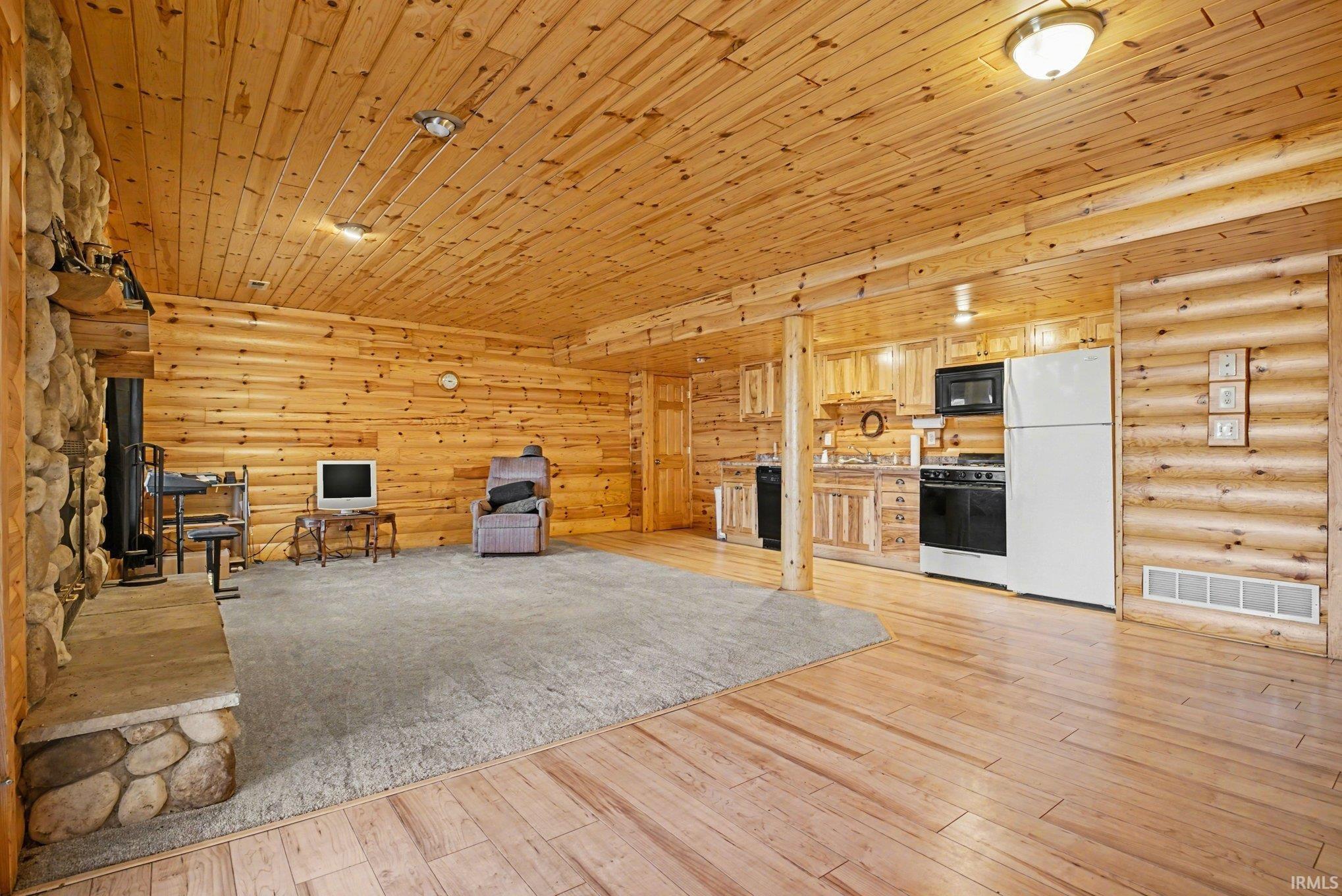 Unfurnished living room featuring rustic walls, wood ceiling, and light wood-style floors