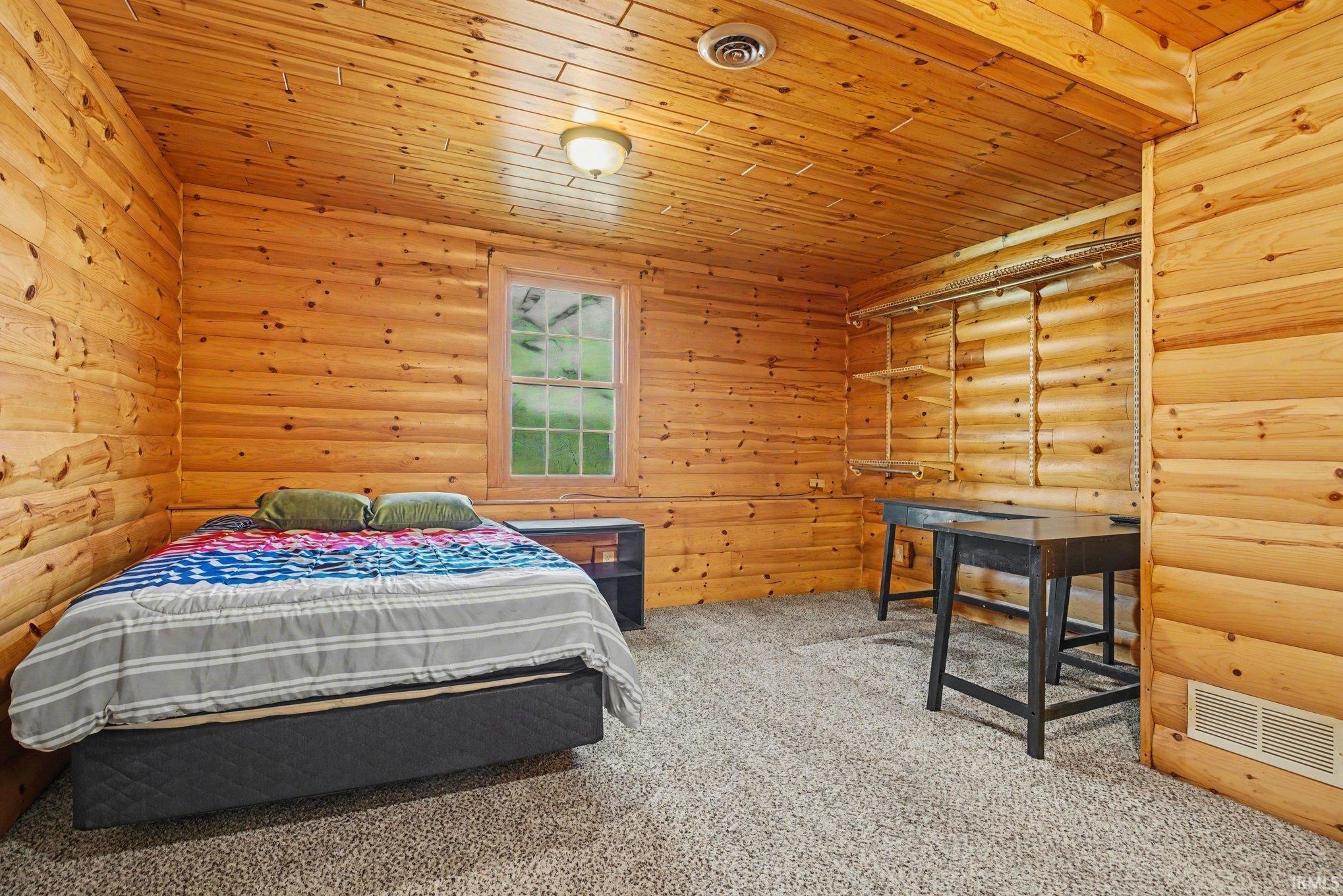 Bedroom featuring log walls, light colored carpet, and wooden ceiling