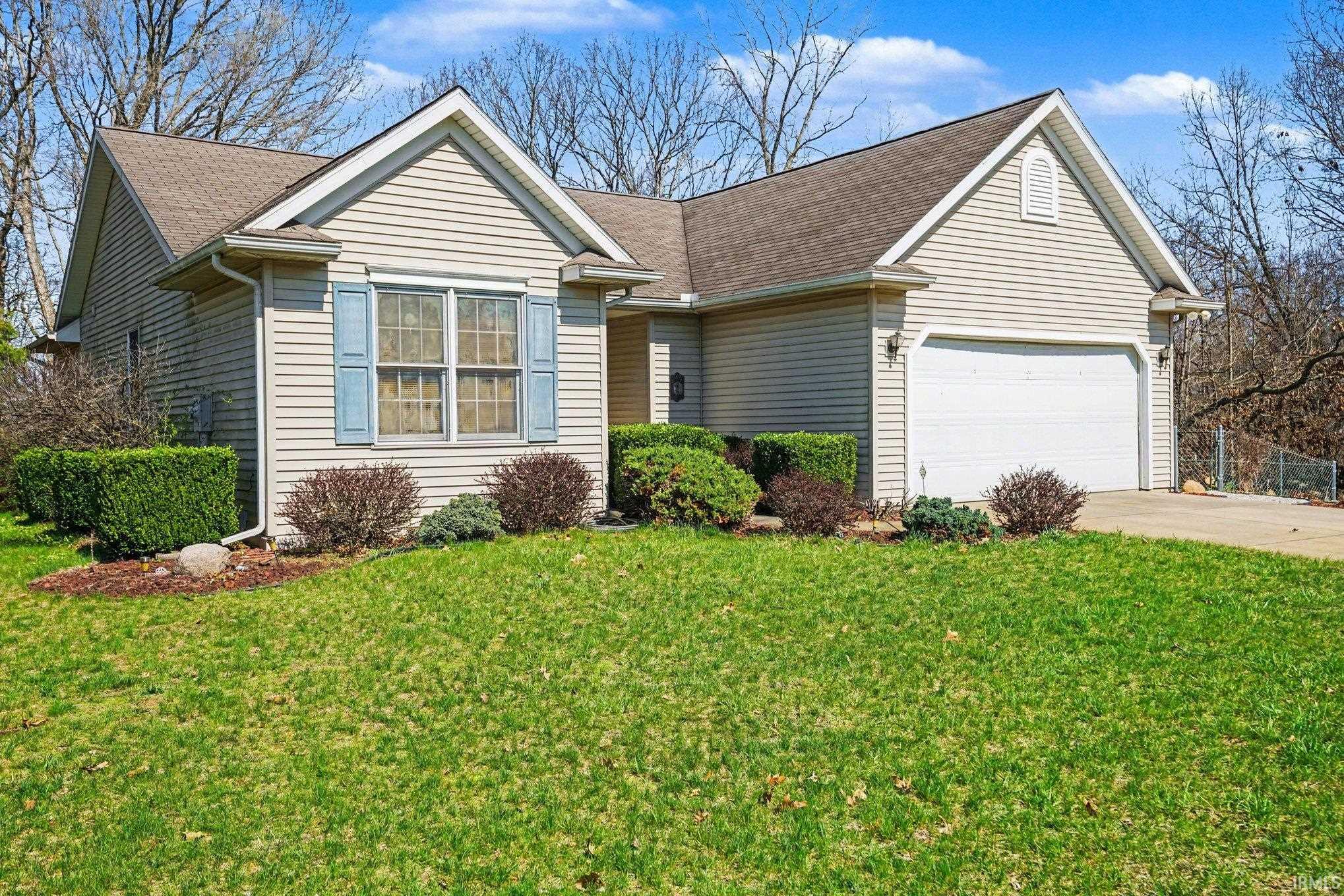 View of front of property featuring a garage, a front yard, concrete driveway, and a shingled roof
