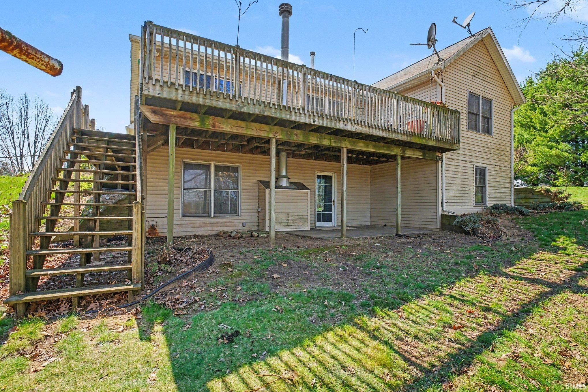 Back of house featuring a deck, a patio area, and a yard