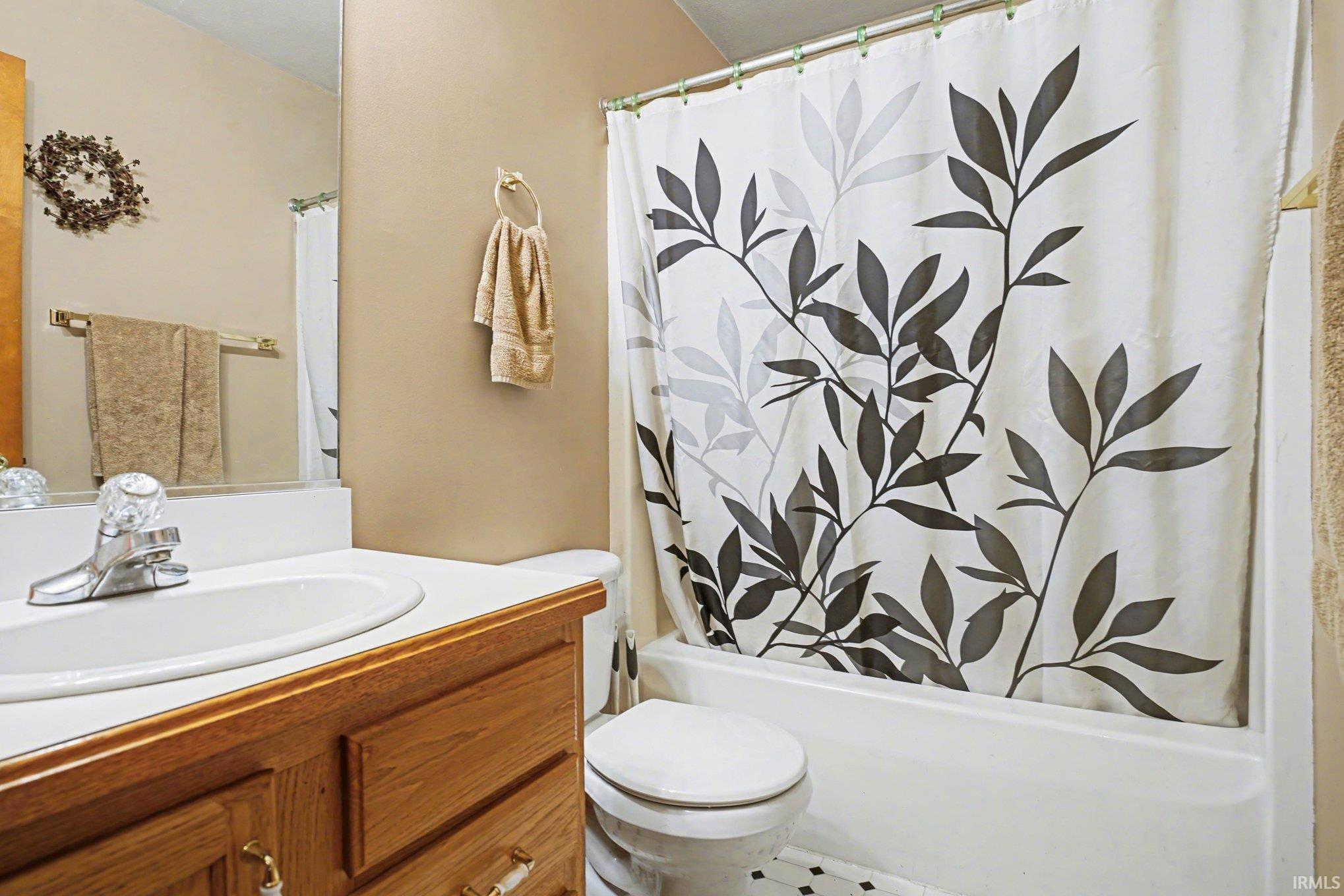 Bathroom featuring vanity and shower / bathtub combination with curtain