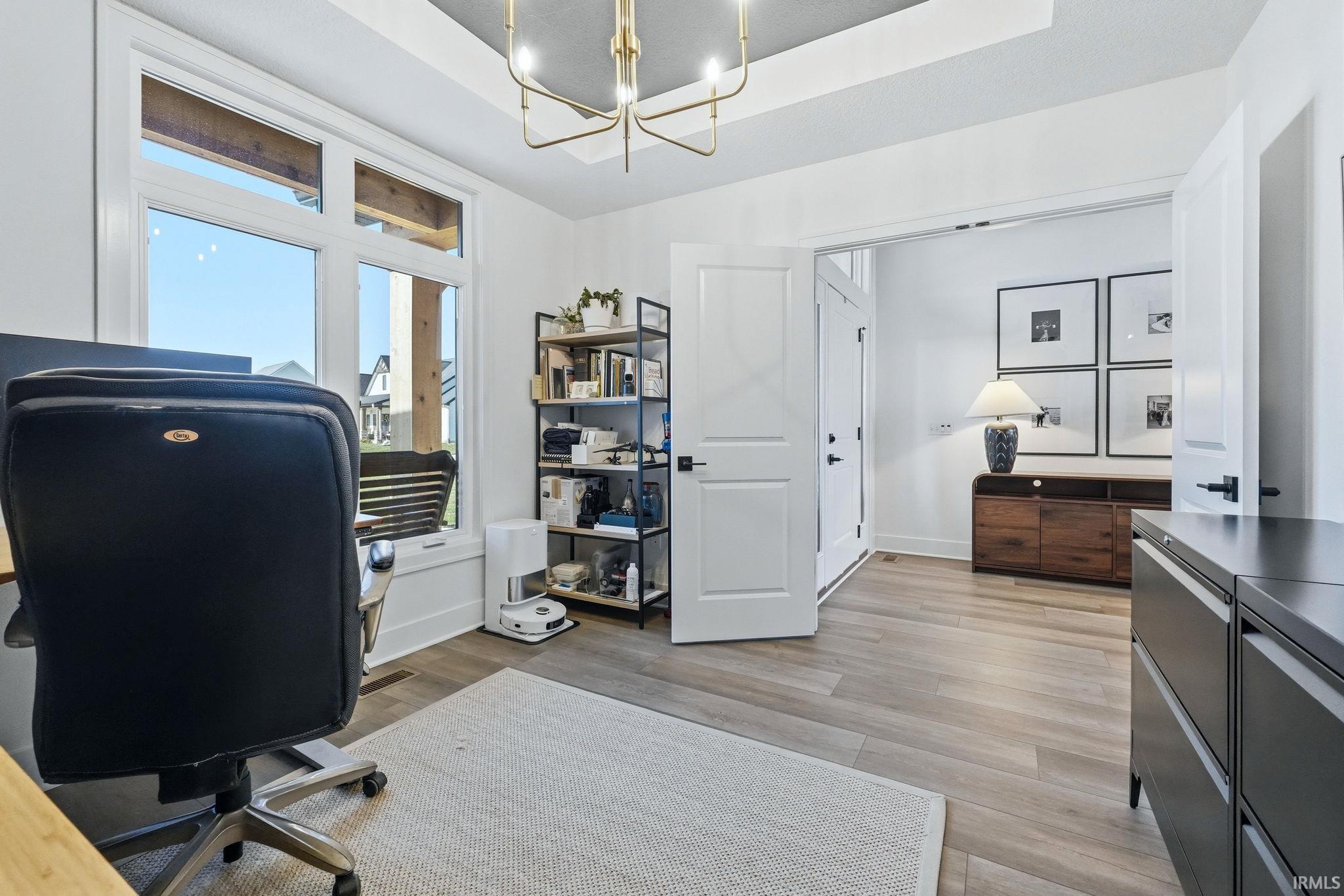 Office with light wood-style flooring and suspended lighting