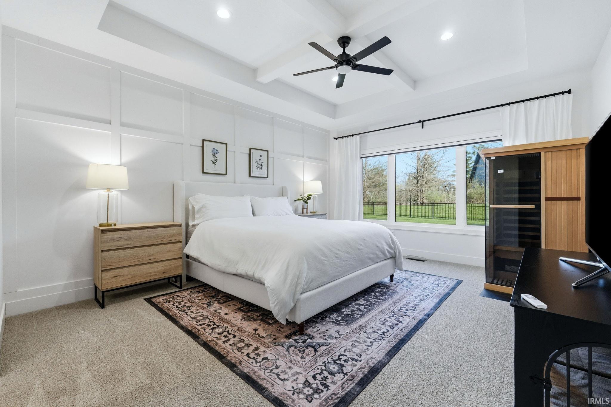 Bedroom with light colored carpet, coffered ceiling, a ceiling fan, recessed lighting, and a decorative wall