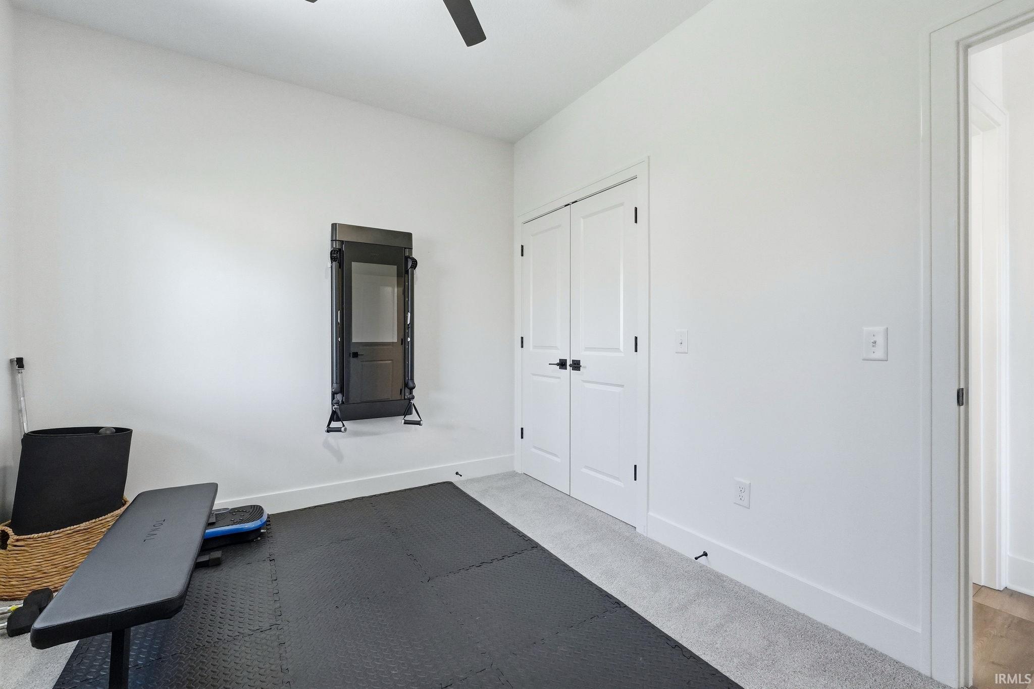 Workout area featuring light colored carpet and ceiling fan