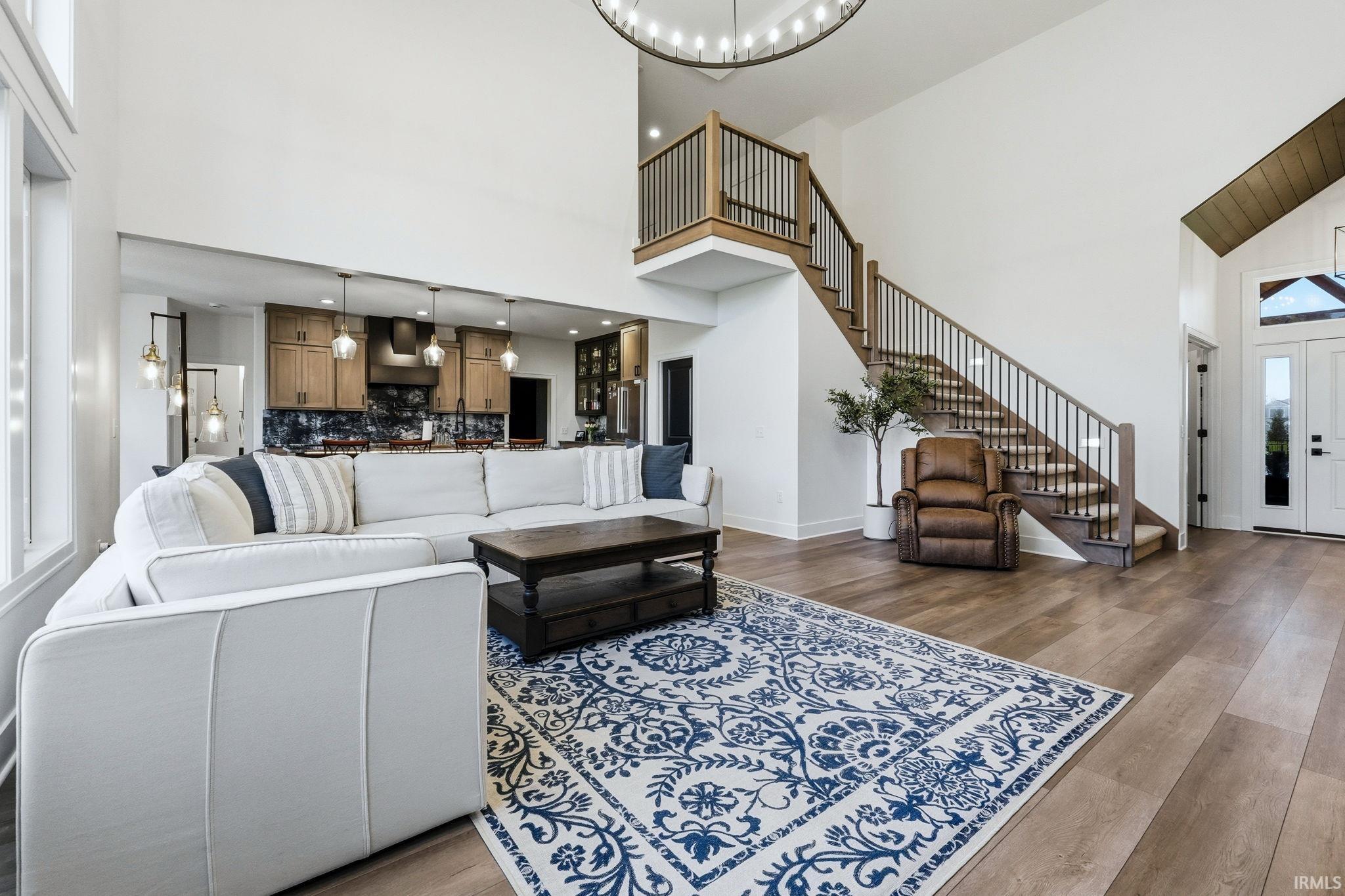 Living room featuring a high ceiling, dark wood-type flooring, and a chandelier