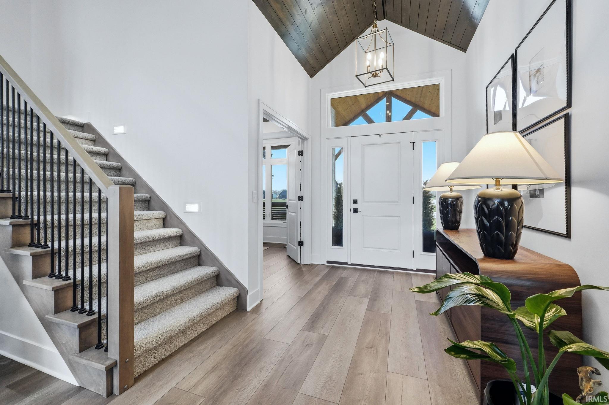 Foyer entrance featuring light wood-type flooring, a high wooden ceiling, healthy amount of natural light, and a chandelier