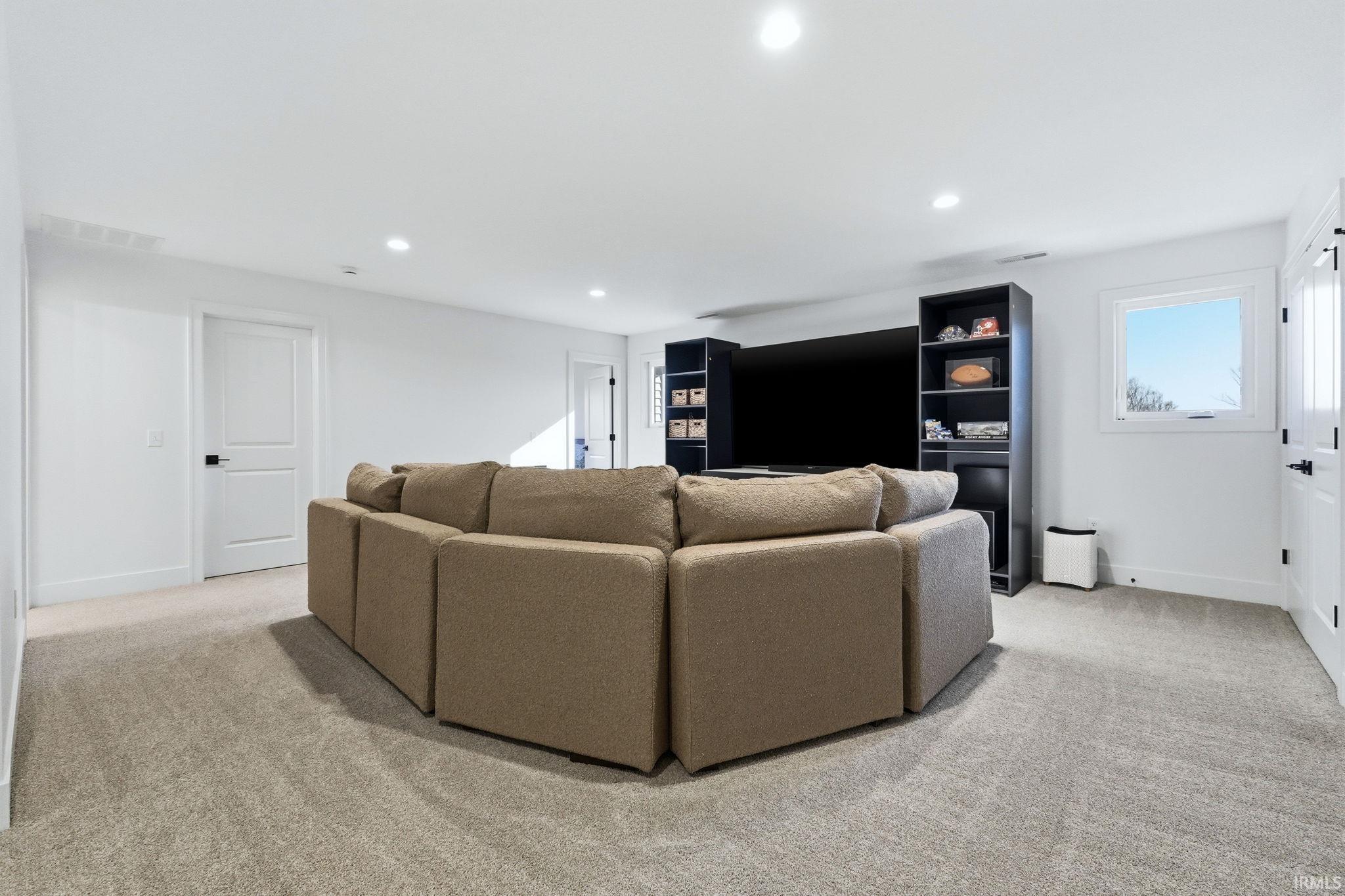 Living area with light colored carpet and recessed lighting