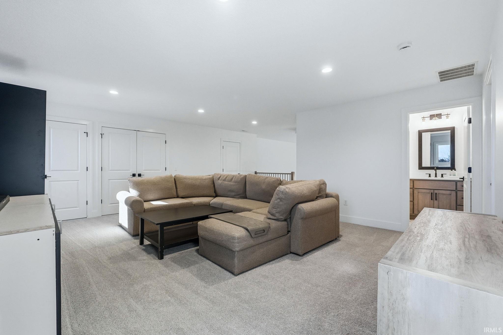 Living area with light colored carpet and recessed lighting