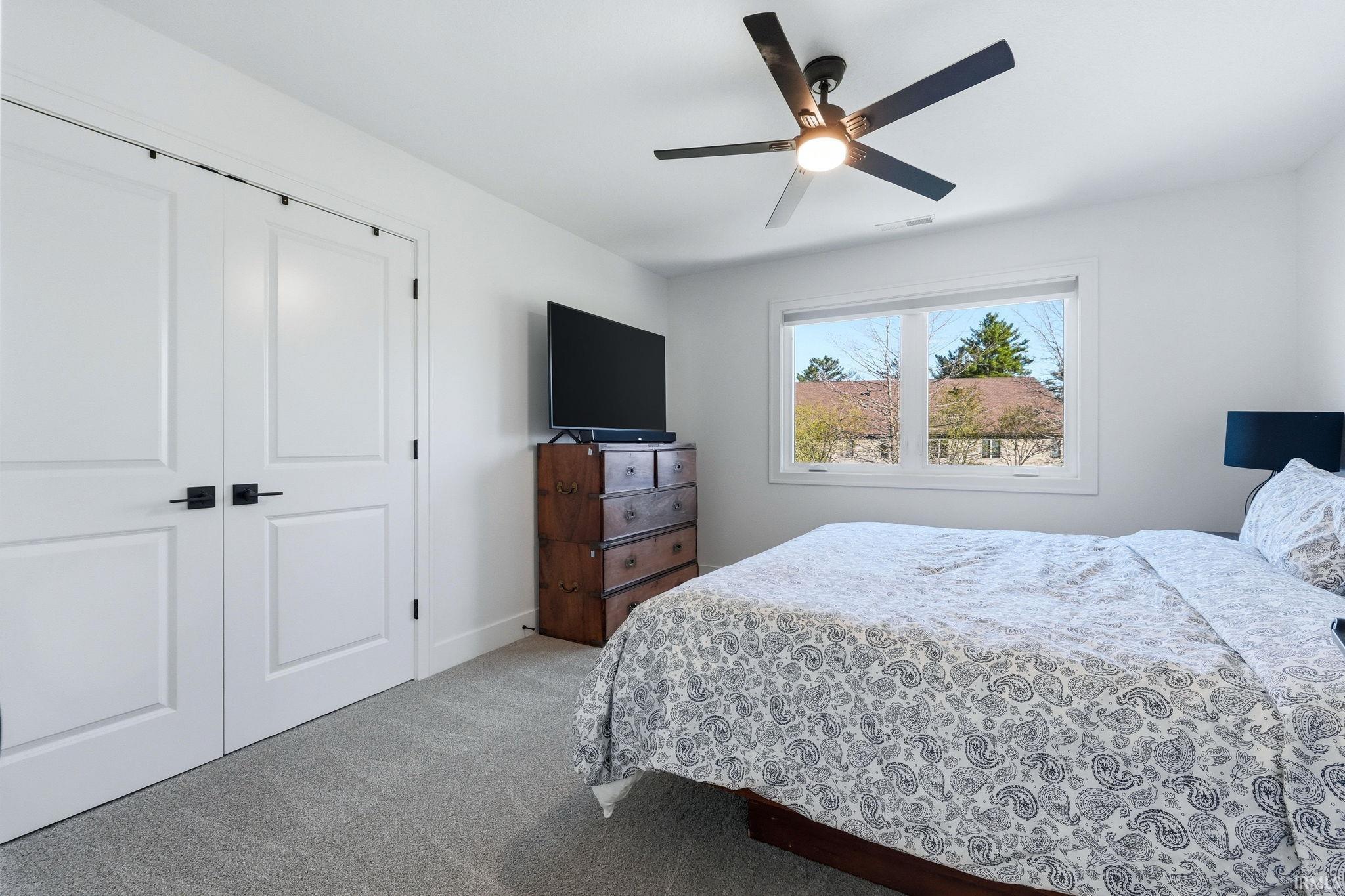 Bedroom featuring light colored carpet, ceiling fan, and a closet