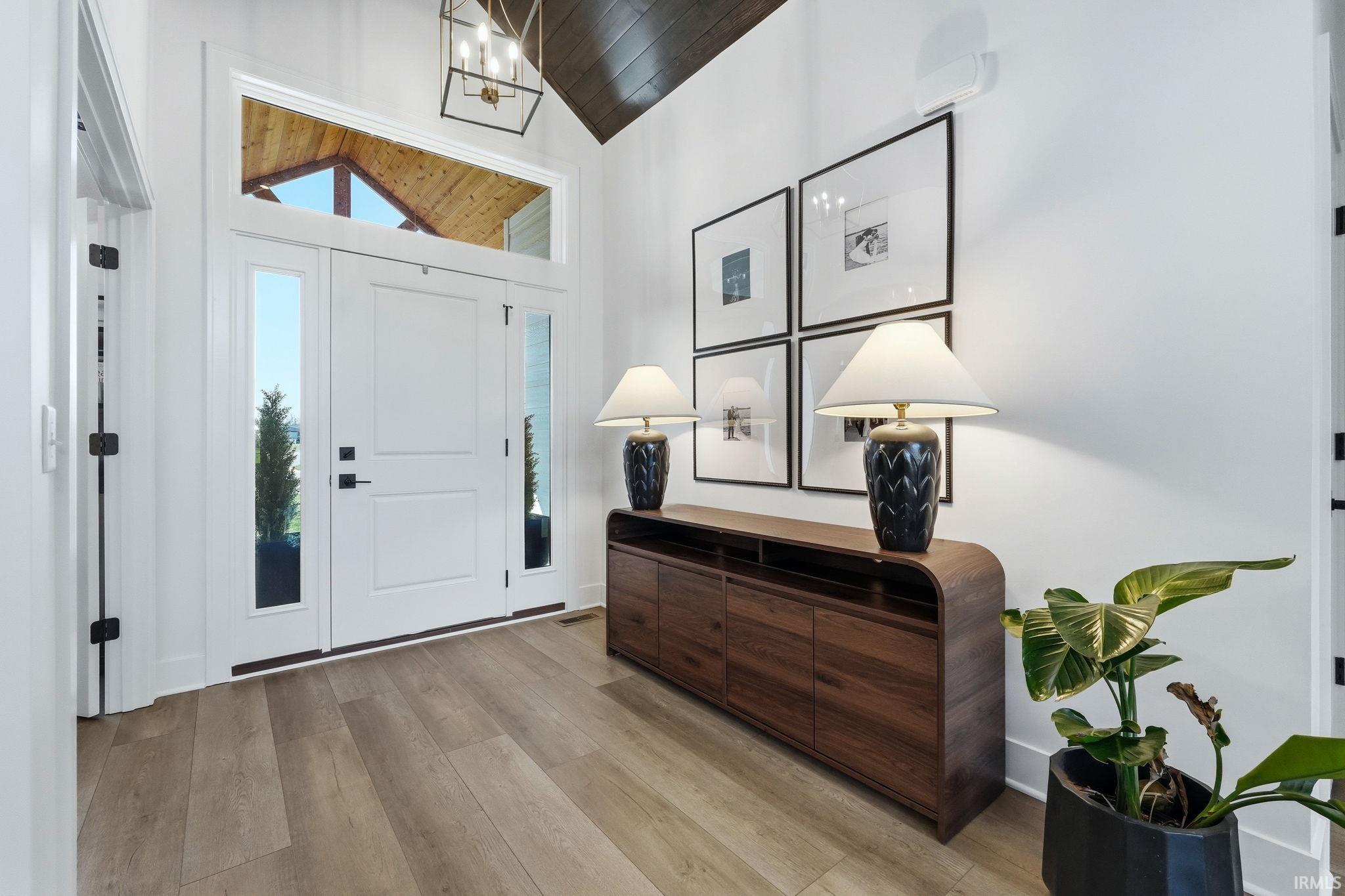 Entrance foyer with light wood-type flooring, a vaulted wood ceiling, and hanging lights