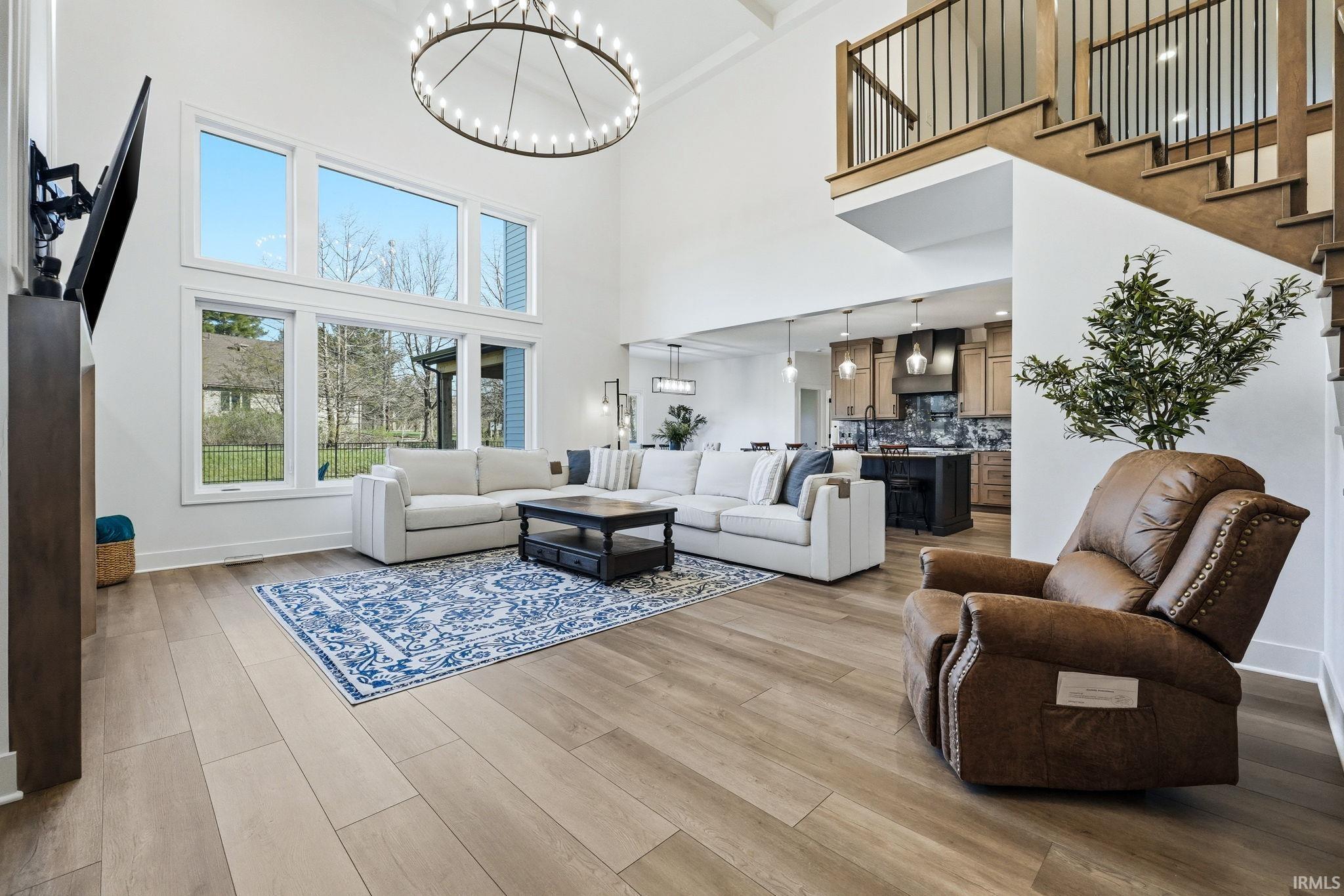 Living area with a chandelier, light wood-type flooring, and a high ceiling