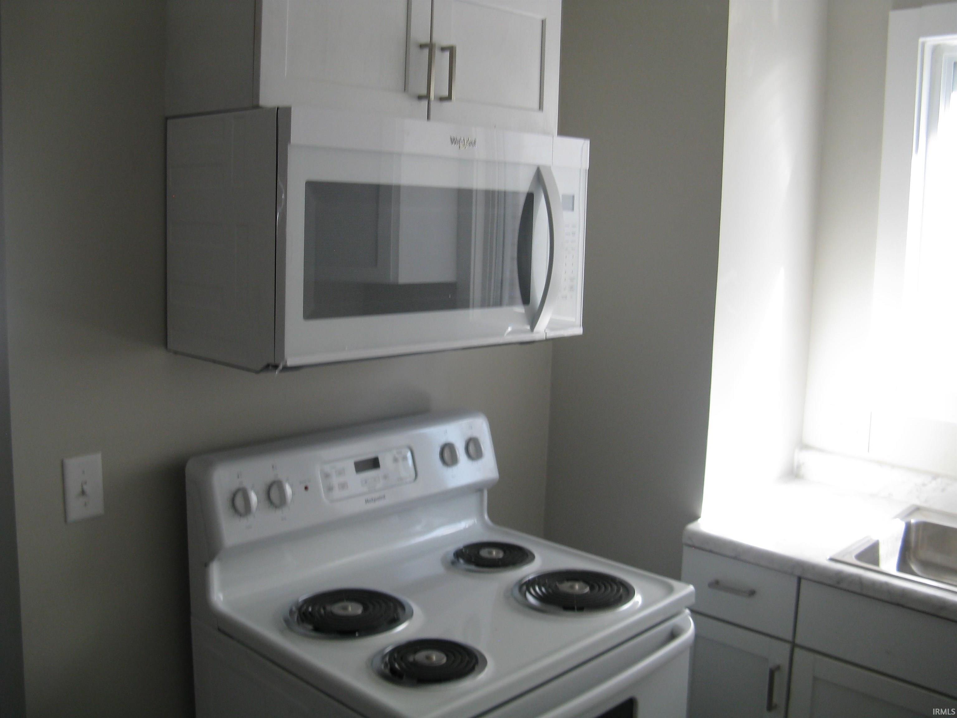 Kitchen featuring white appliances, light countertops, and white cabinetry