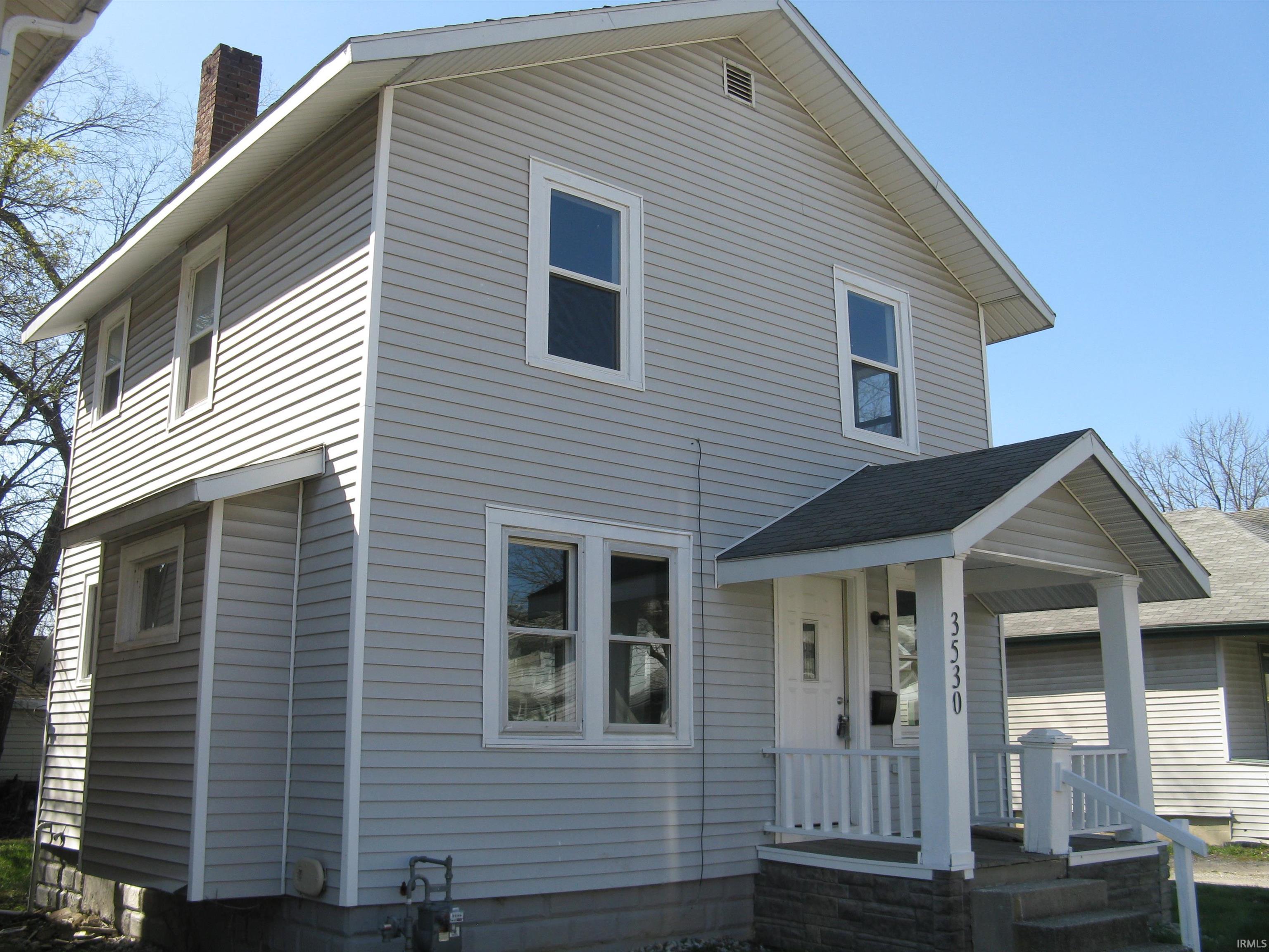 View of front of house featuring a chimney, roof with shingles, and a porch