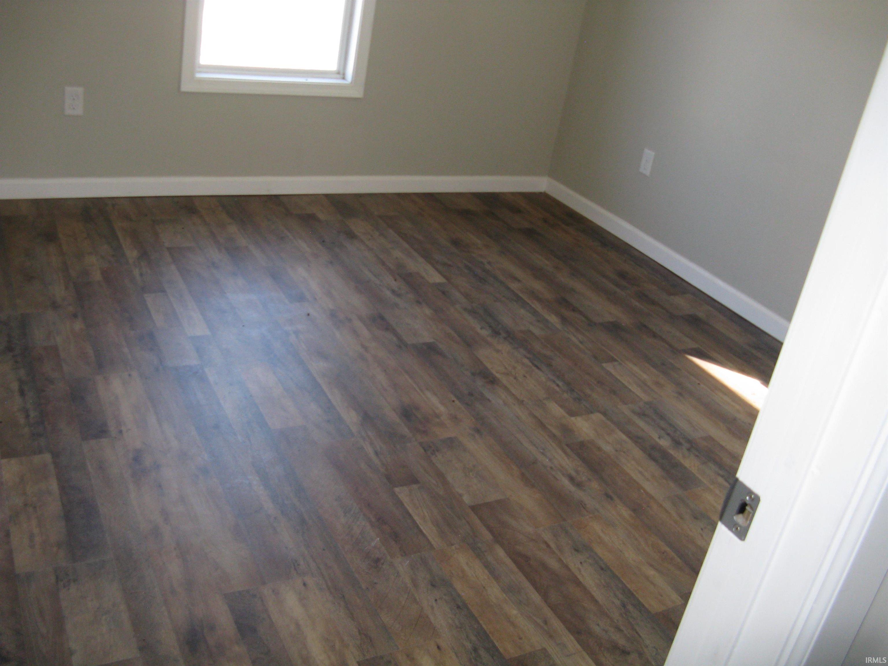 Empty room with dark wood-style flooring and baseboards