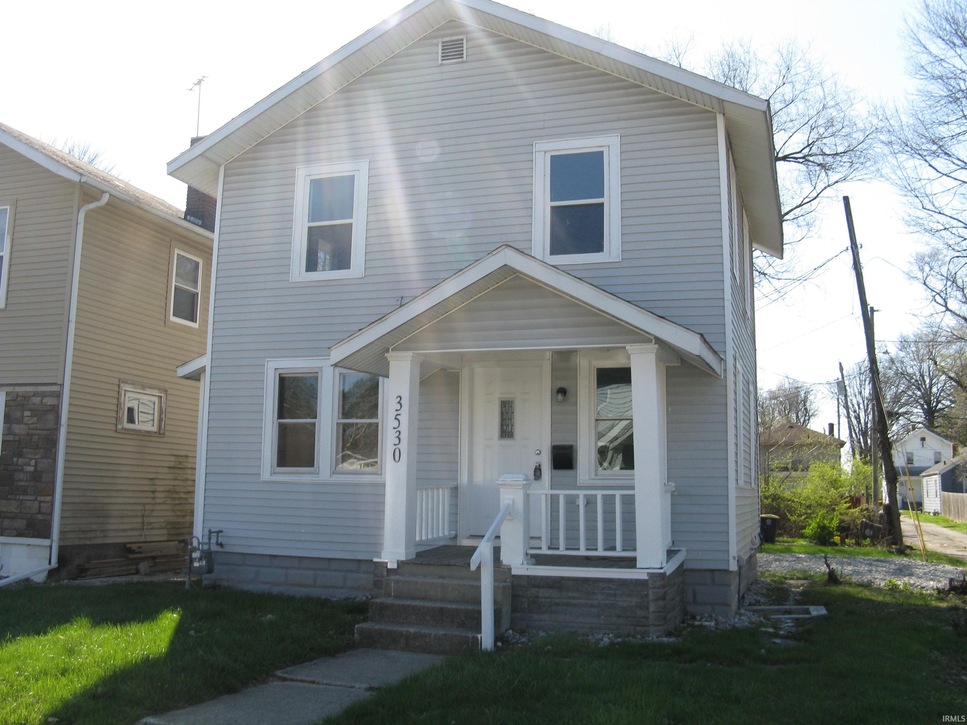 View of front of home with a porch and a front lawn