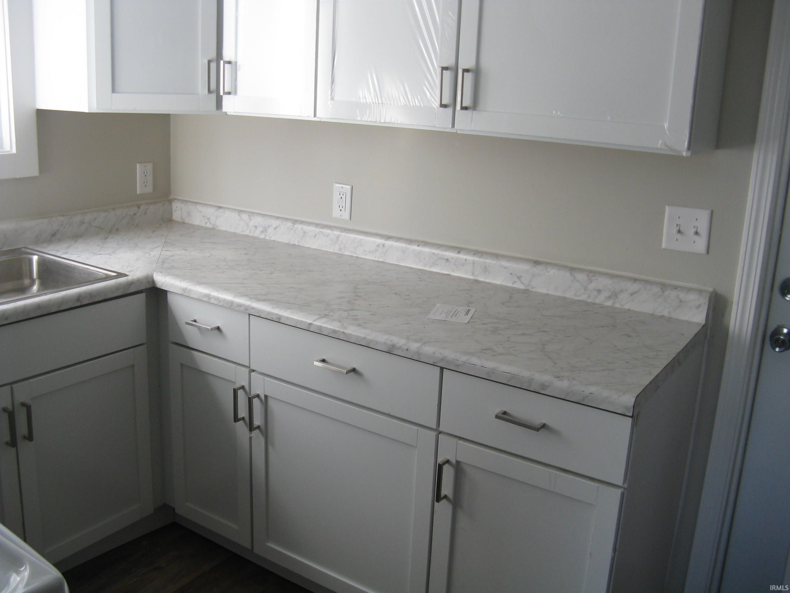 Kitchen with light countertops, white cabinets, and dark wood finished floors
