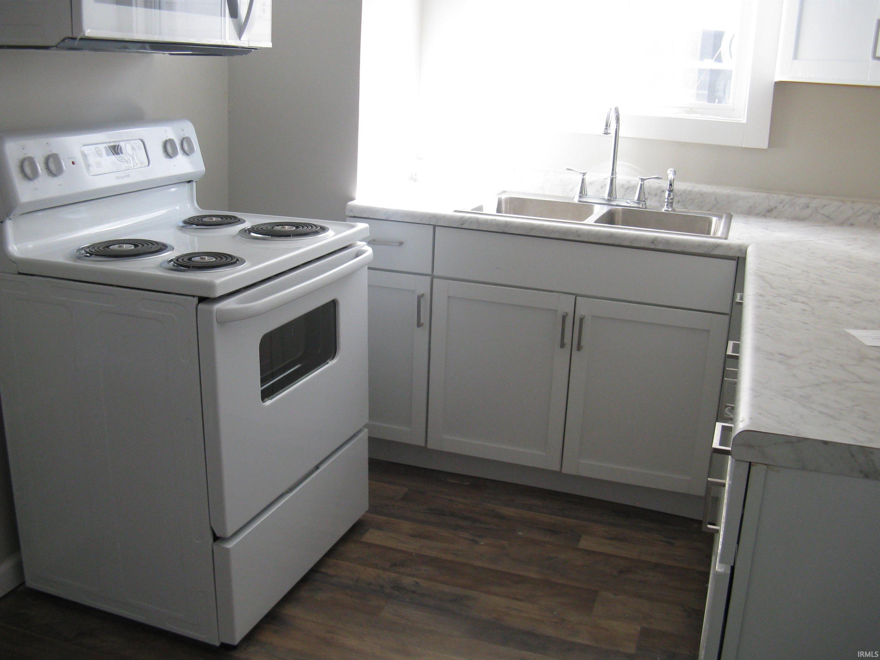 Kitchen featuring white electric stove, light countertops, dark wood-style floors, and gray cabinets