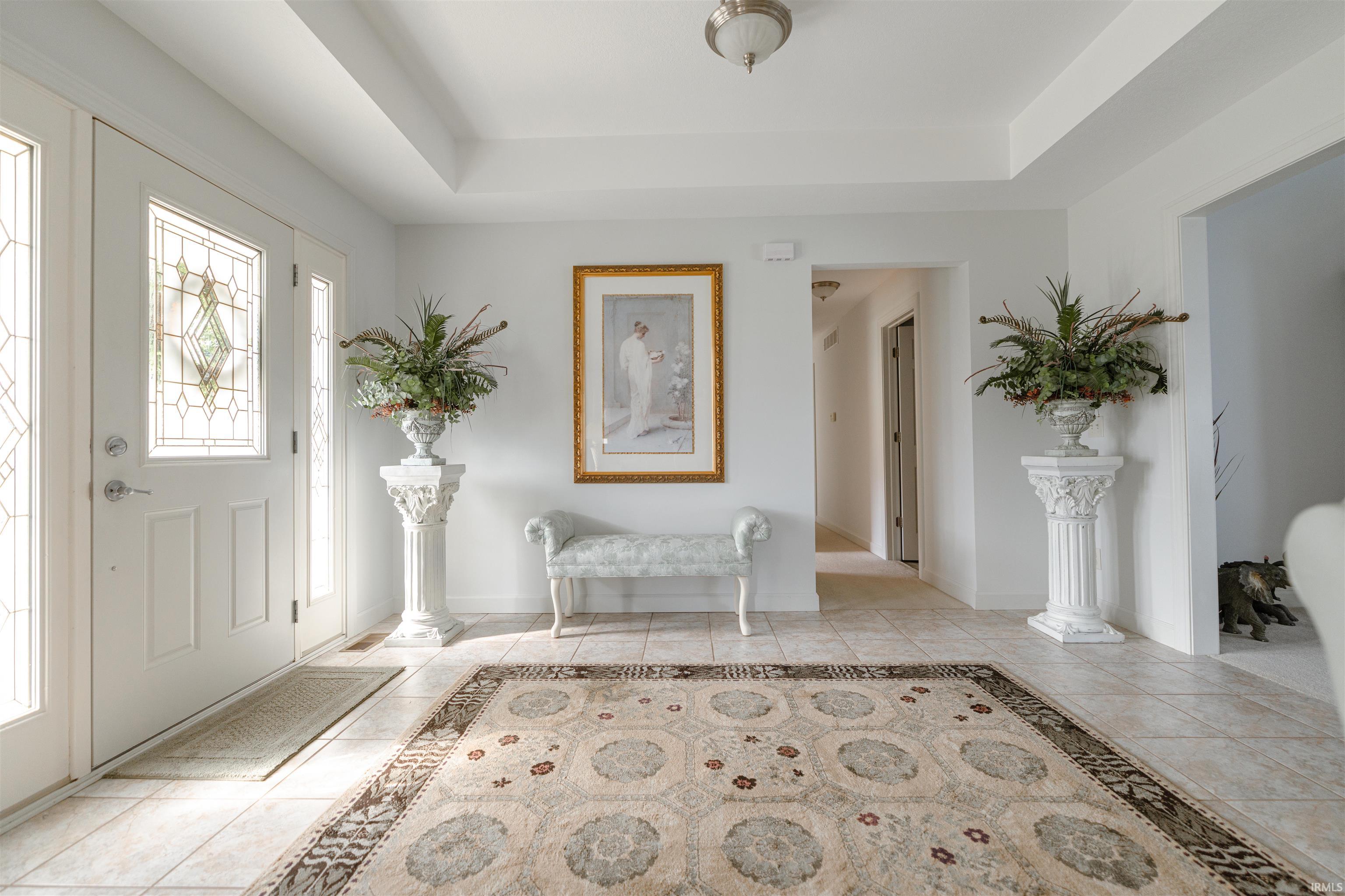 Entryway with a tray ceiling and light tile patterned flooring