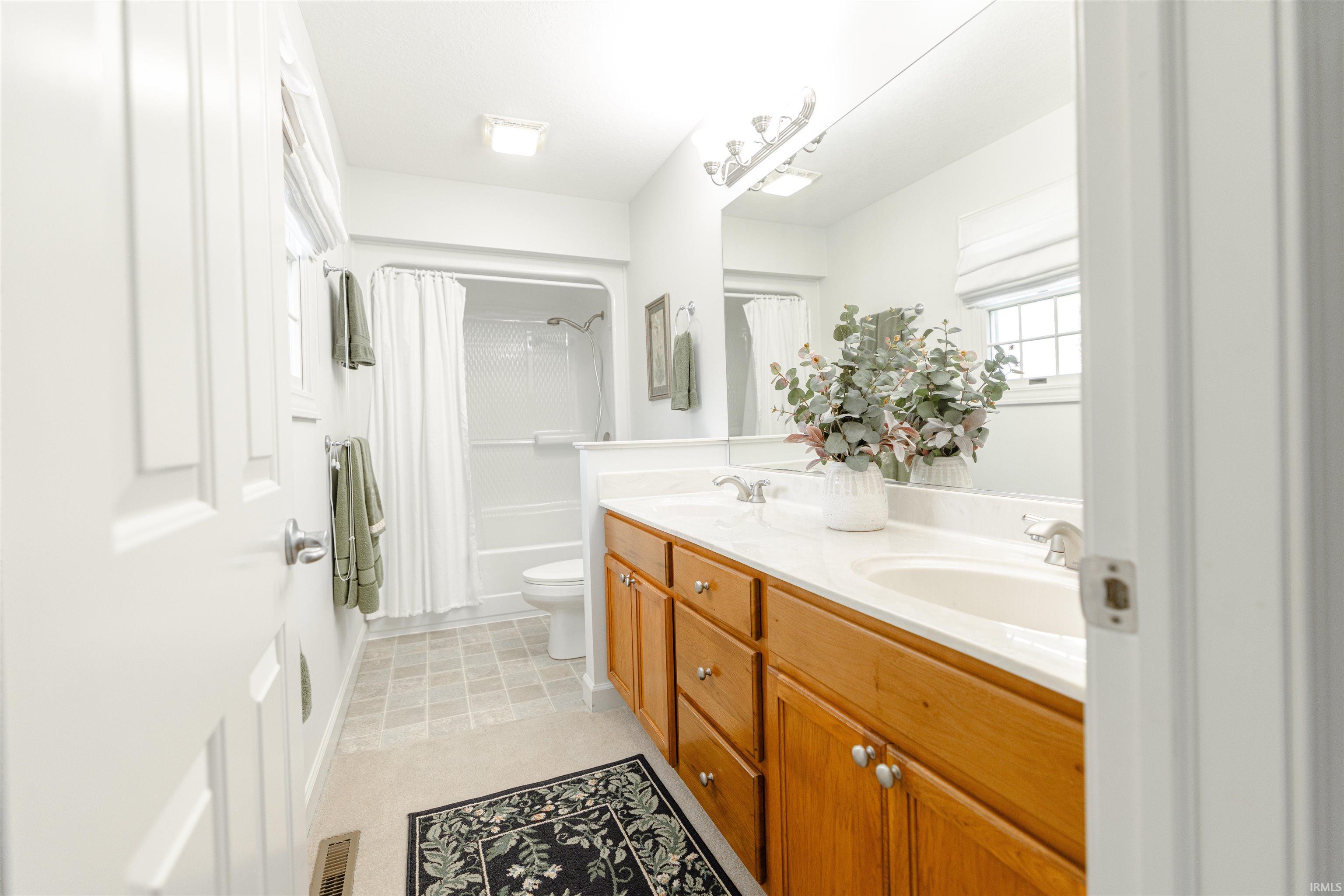 Bathroom featuring double vanity and shower / tub combo with curtain