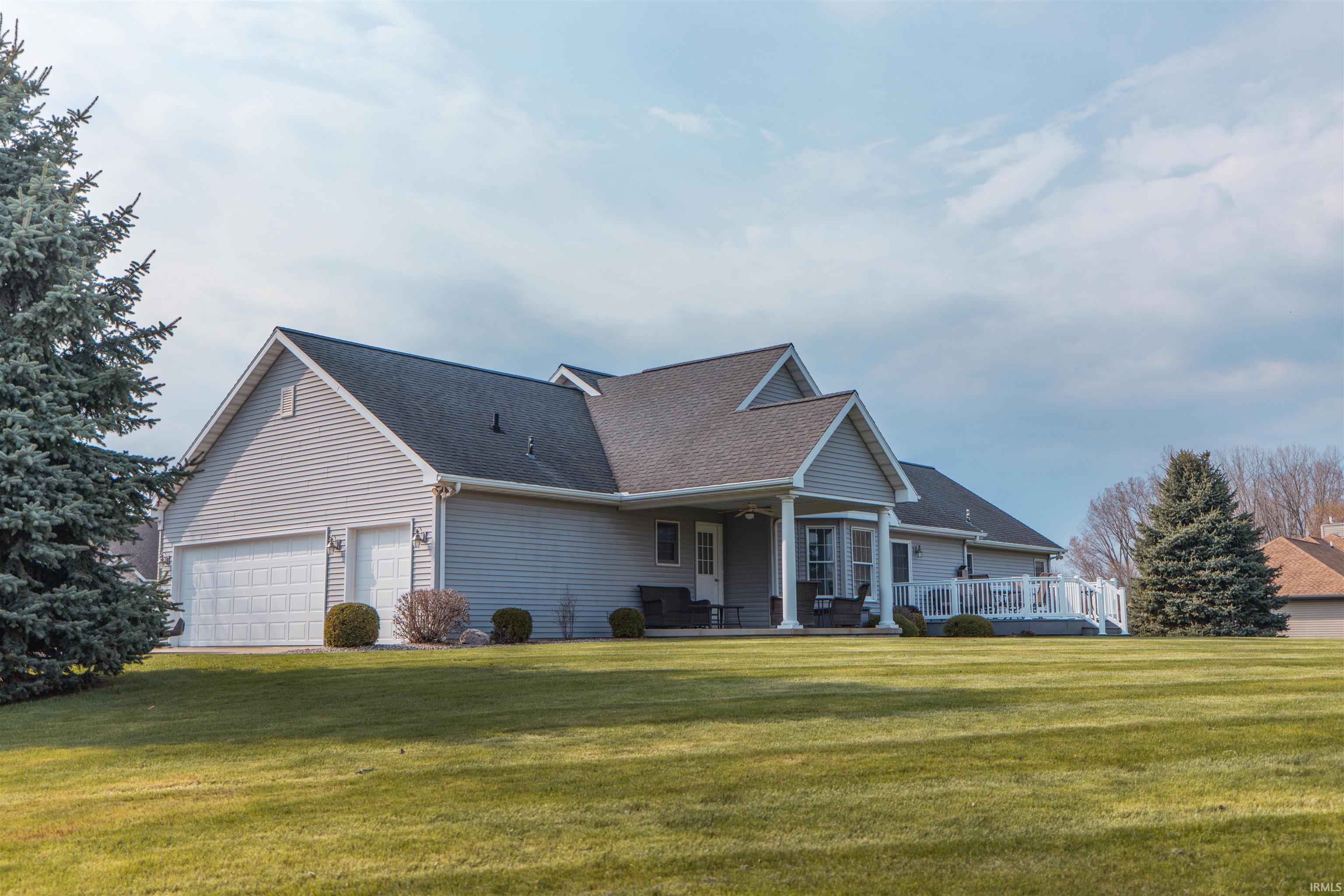 View of front of home featuring a front yard, a porch, a shingled roof, and a garage