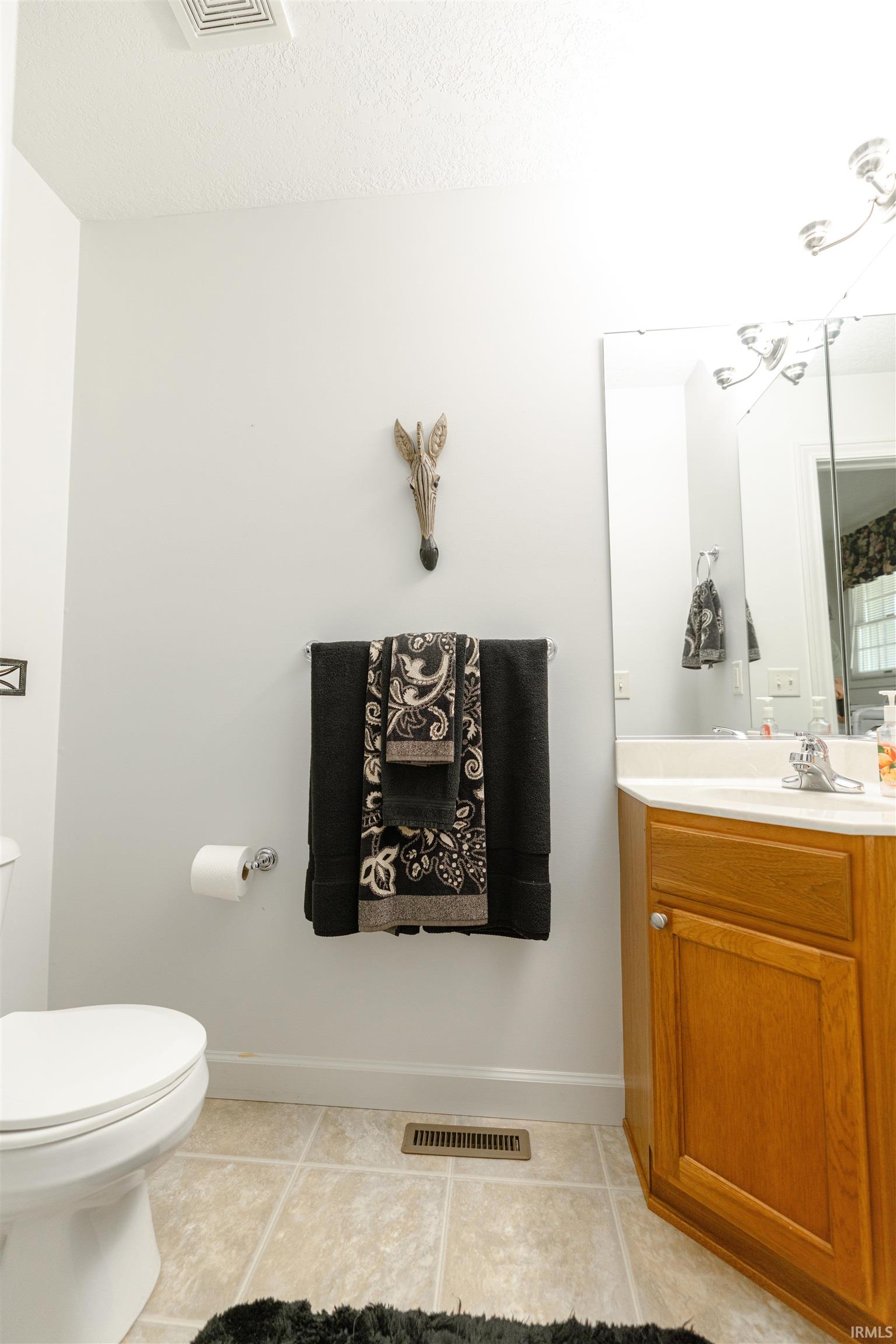 Bathroom featuring vanity, light tile patterned flooring, and a textured ceiling